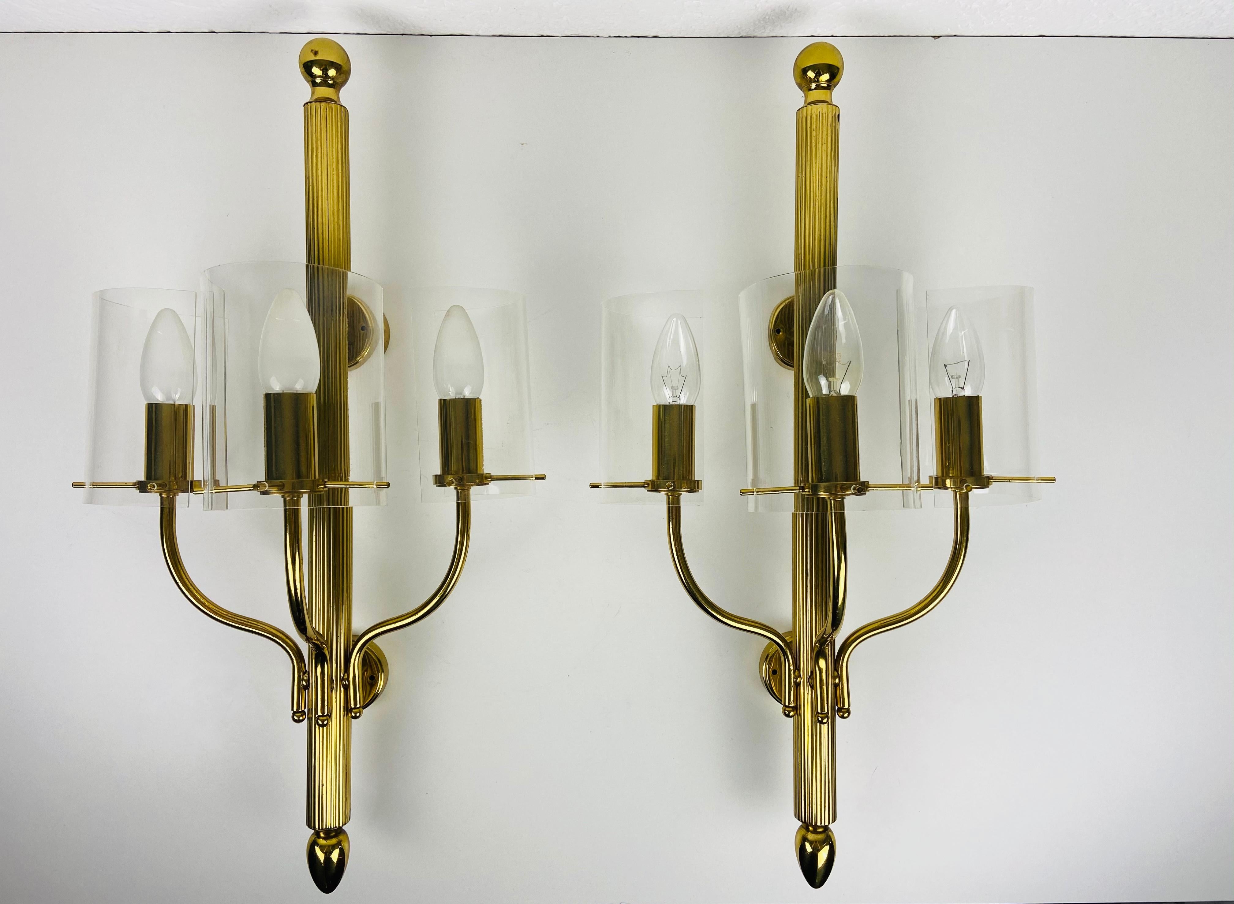 A pair of very large Mid-Century Modern wall lamps made in the 1950s. They can perfectly be mounted on the wall. The shade of the lights is made of perxpex with a brass frame.

The light requires three E14 light bulbs. Works with both on