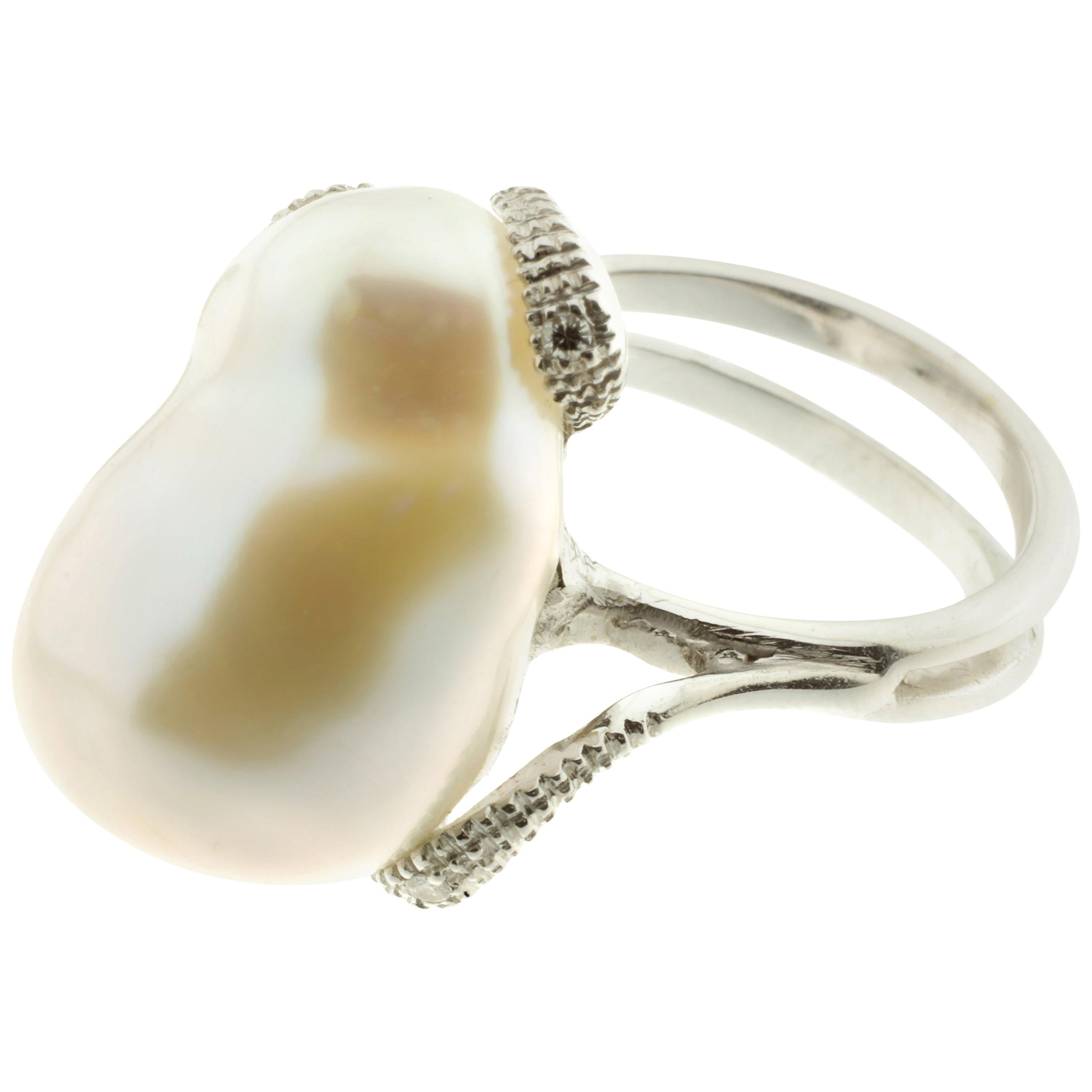 This stunning double band cocktail ring has been masterfully created entirely by hand from 18-karat white gold and features a large cultured pearl, positioned lengthwise, set with white diamonds. 

Measuring about 21.5 millimetres (along the
