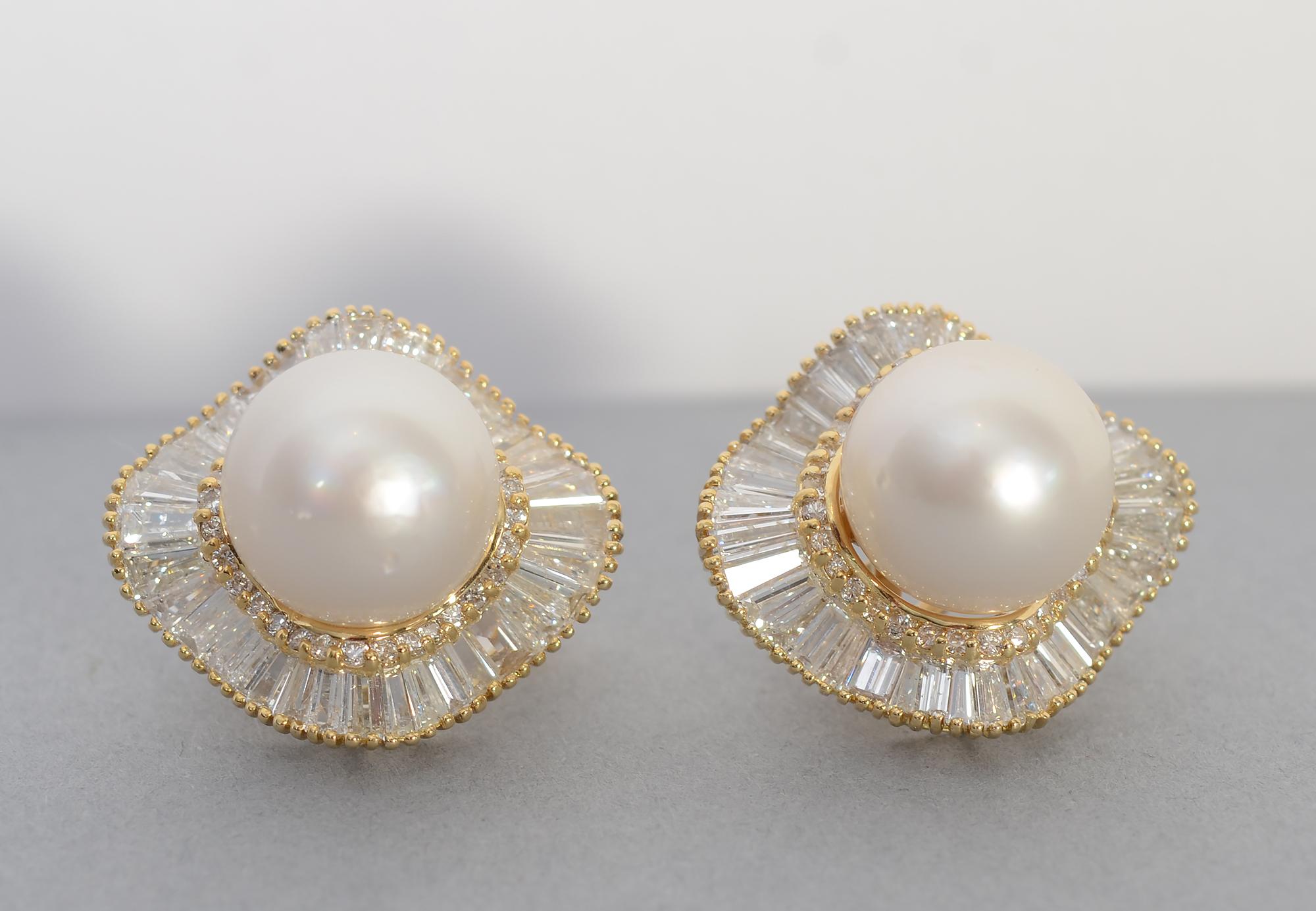 Dramatic diamond earrings centered with pearls, each of which is slightly larger than 13 mm.
Surrounding the pearl is a row of round diamonds. Outside of that is an undulating row of baguette cut diamonds. The total diamond weight is 7 carats. The
