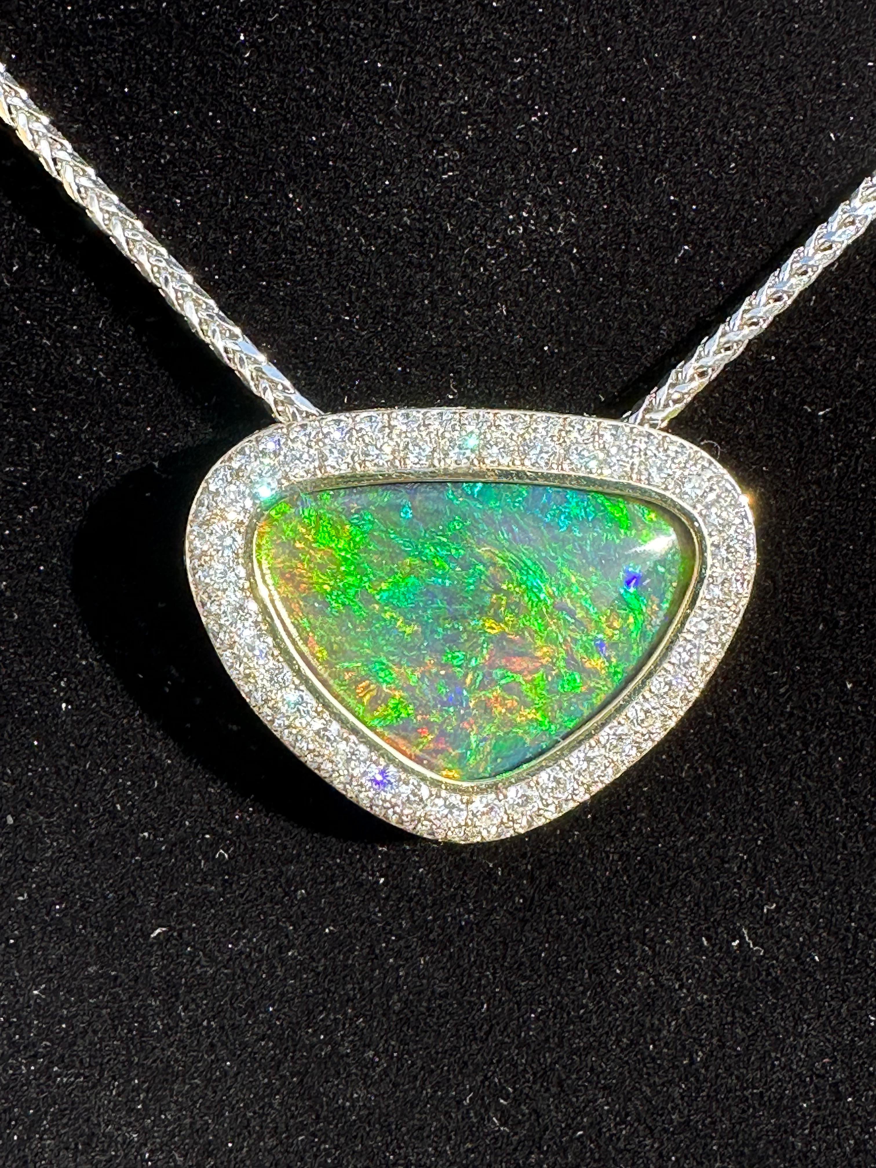 Very showy, finest rare gem quality, 18 karat white and yellow gold huge natural Australian black opal and diamond estate pendant necklace features a 37.76 carat fiery some what triangular shaped natural opal in the center, surrounded by a double