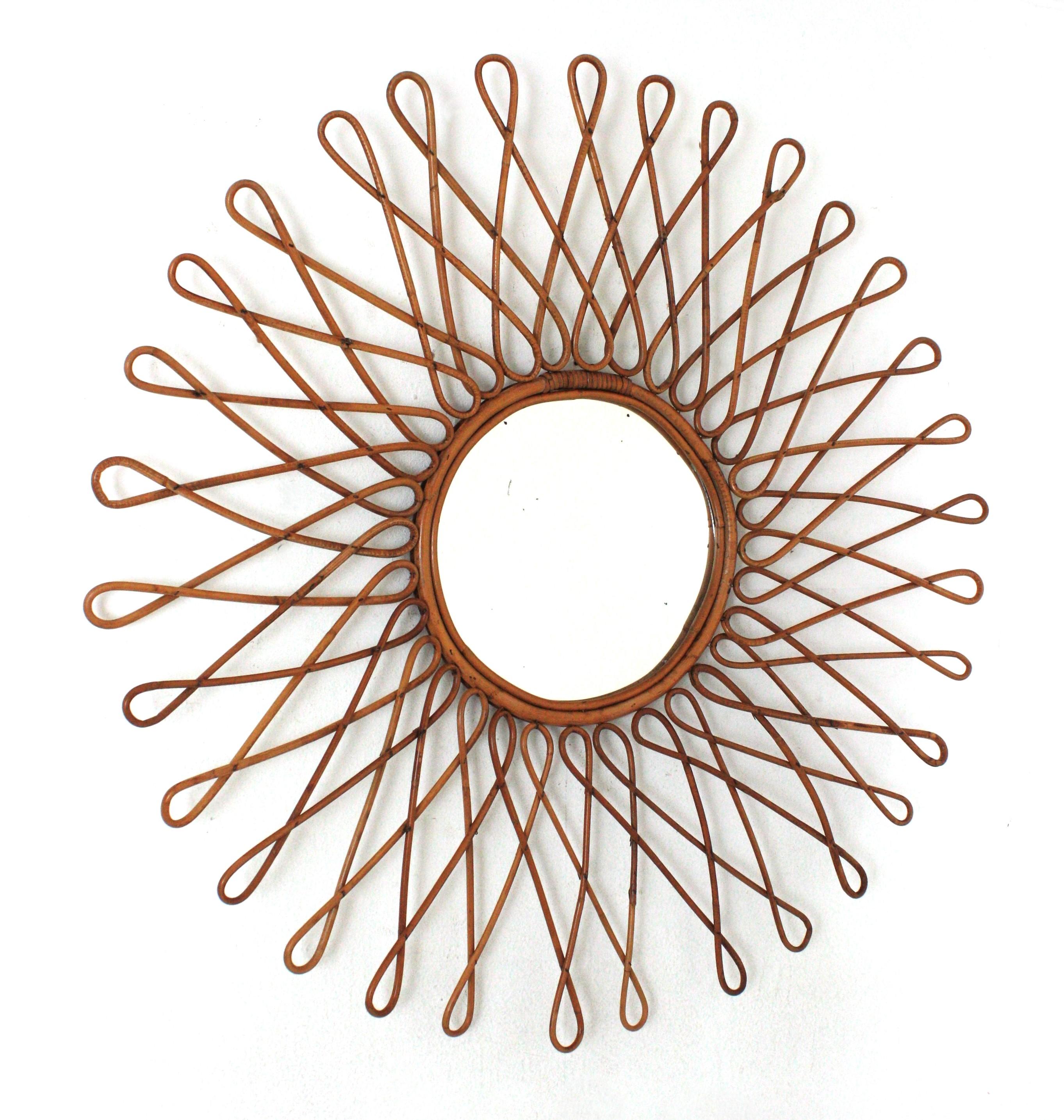 XXL Midcentury rattan sunburst starburst wall mirror. France, 1960s.
This mediterranean wall mirror features a round mirror glass framed by rattan canes with loop endings creating an eye-catching sunburst- starburst.
It has all the freshness and
