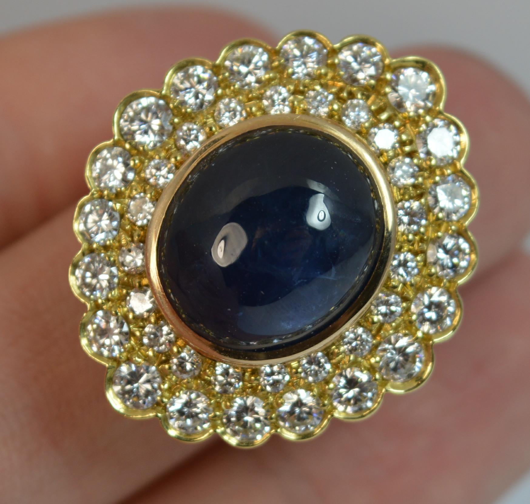 A stunning Sapphire and Diamond cluster or cocktail ring.

A heavy and chunky 18 carat yellow gold example.

Designed with a large oval sapphire cabochon to the centre. 12mm x 13.5mm.

Surrounding are many round brilliant cut diamonds. VVS - VS