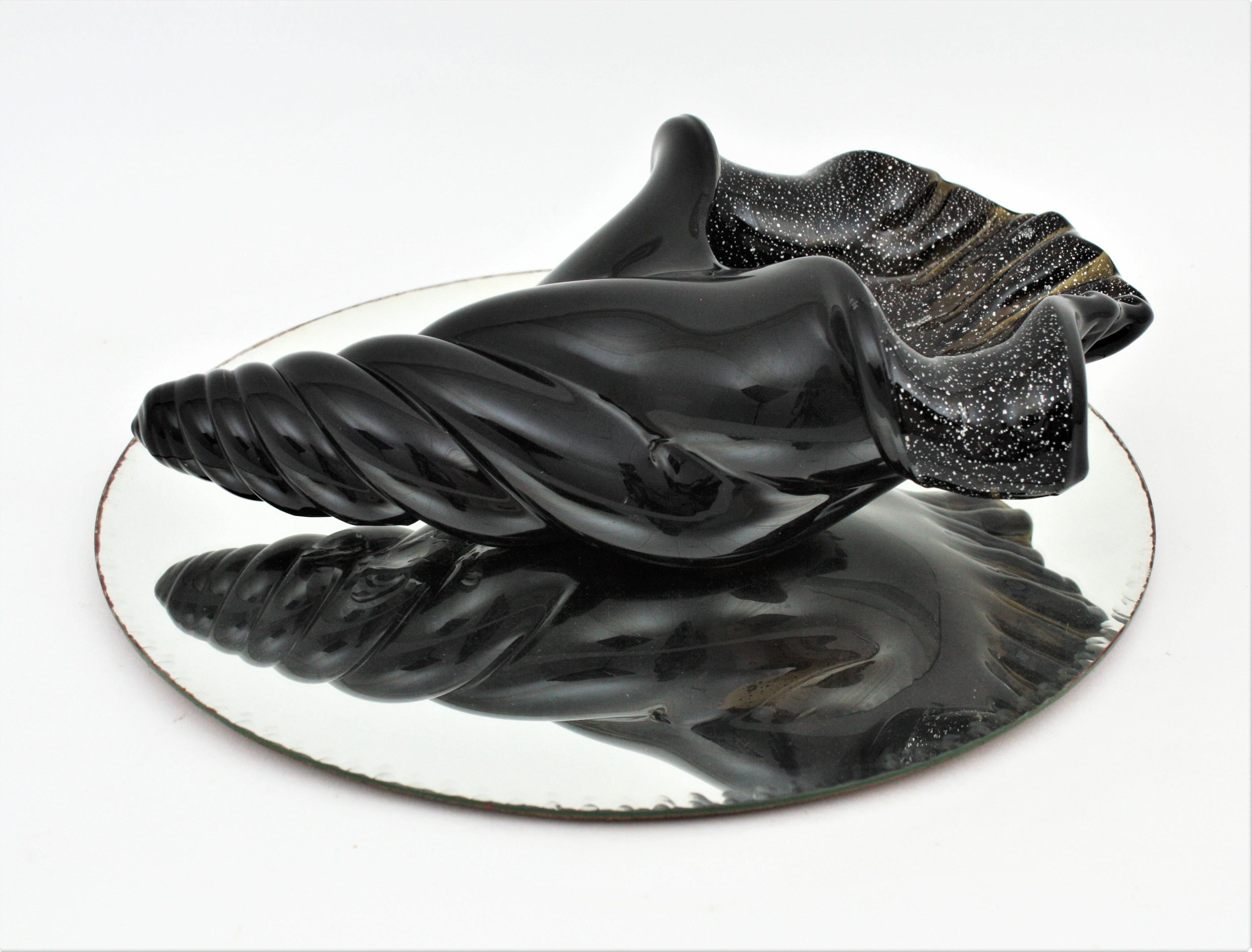 Massive hand blown black Murano glass conch seashell with aventurine silver flecks. Attributed to Archimede Seguso. Italy, 1950s.
This finely executed glass conch shell bowl /centerpiece is heavily decorated with silver flecks and controlled