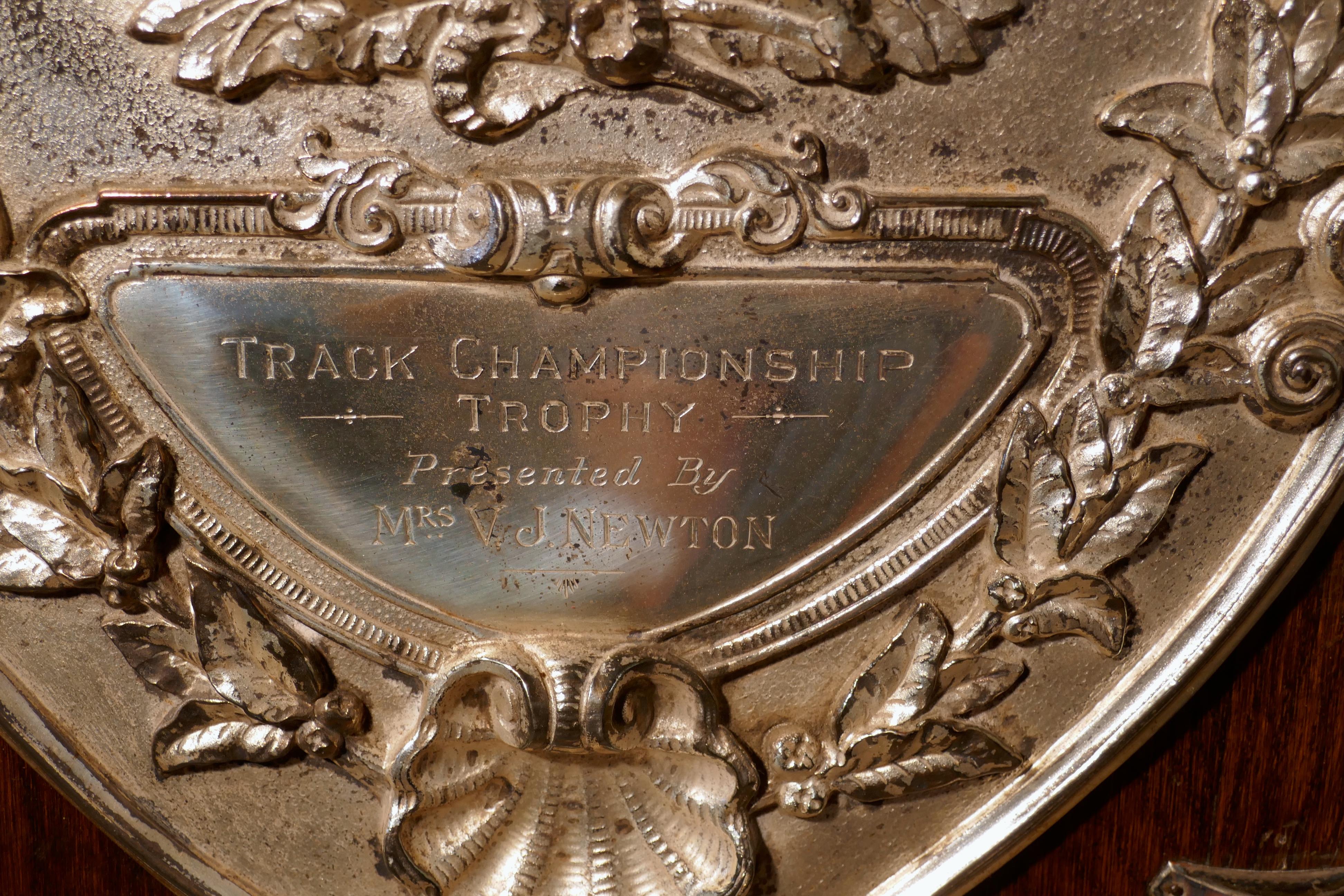 Huge Silchester Cycling Club Track Championships shield trophy

This is a large piece, the oak shield has an embossed silver plated mount, in the centre there is an oval cartouche with speeding cyclist, above a ribbon engraved with the name of the