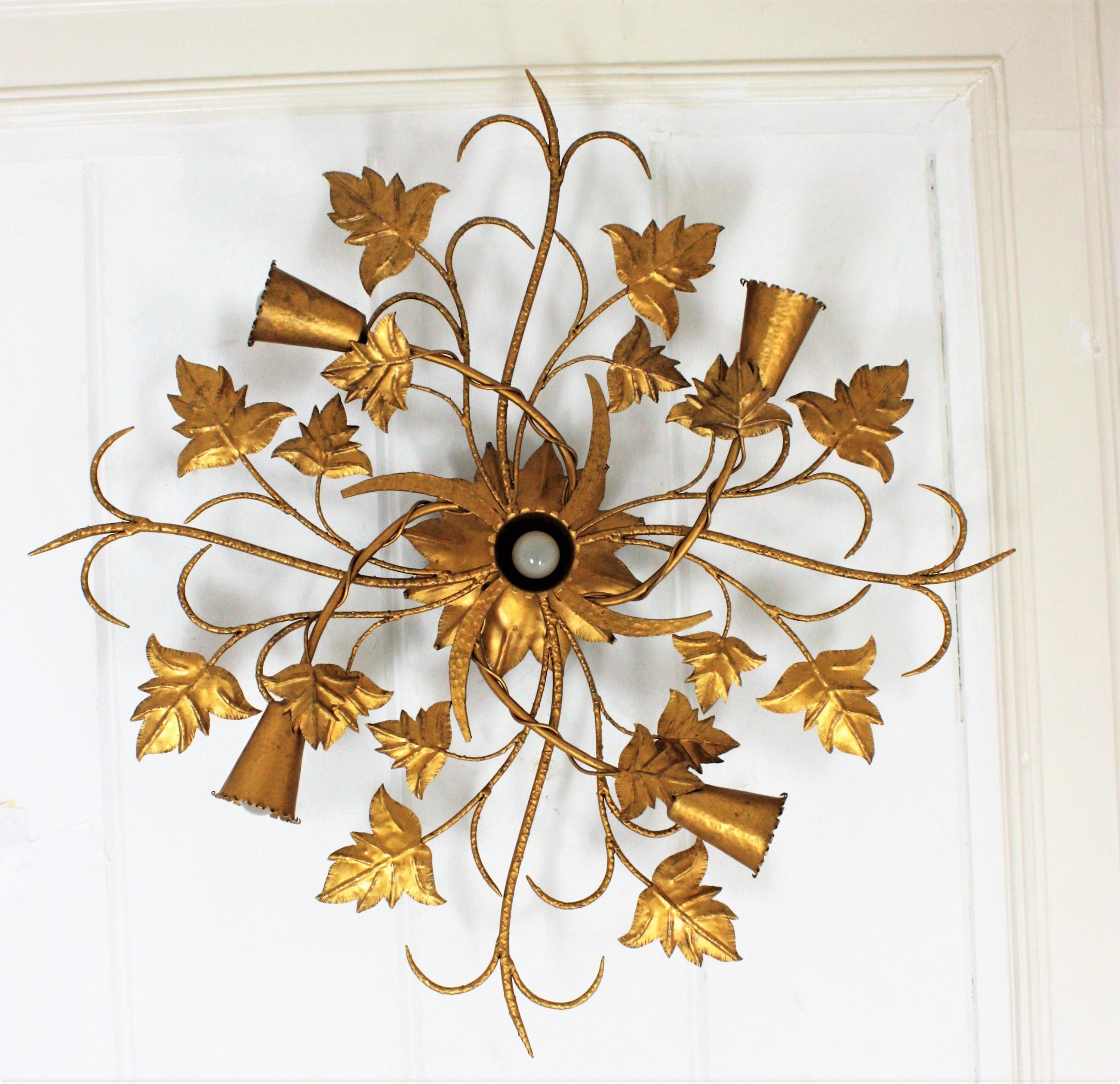 Massive Spanish Art Nouveau style gilt iron floral ceiling light fixture or chandelier, Spain, 1930s-1940s.
This magnificent flush mount lamp features a foliate design structure with four branches ending with conical bulb holders and a central