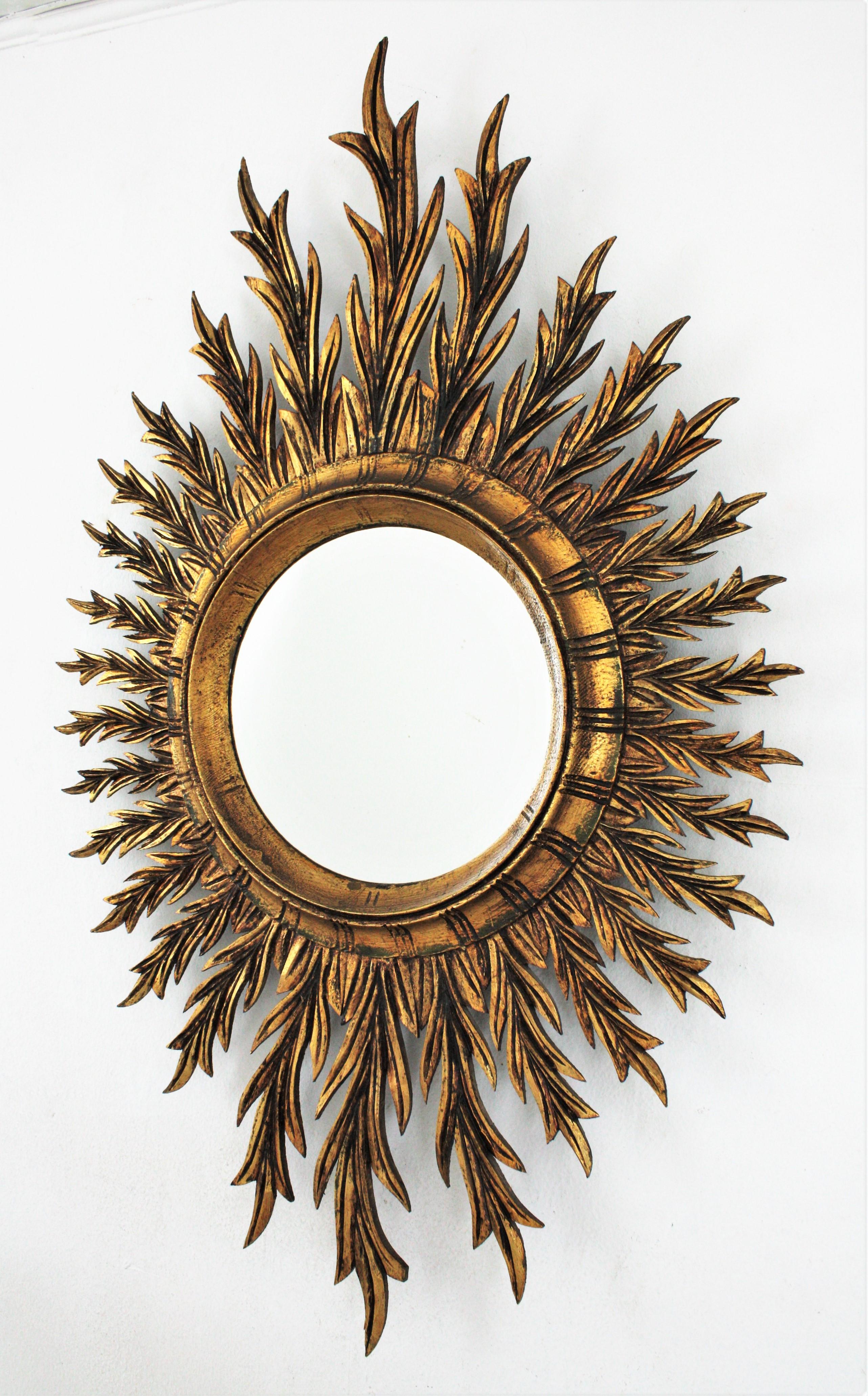 Large Spanish Sunburst Oval Mirror in Giltwood, 1950s
An amazing finely carved giltwood oval shaped starburst /sunburst mirror with gold leaf finish in the style of Hollywood Regency, Spain, 1950s-1960s.
This mirror has a richly carved frame with