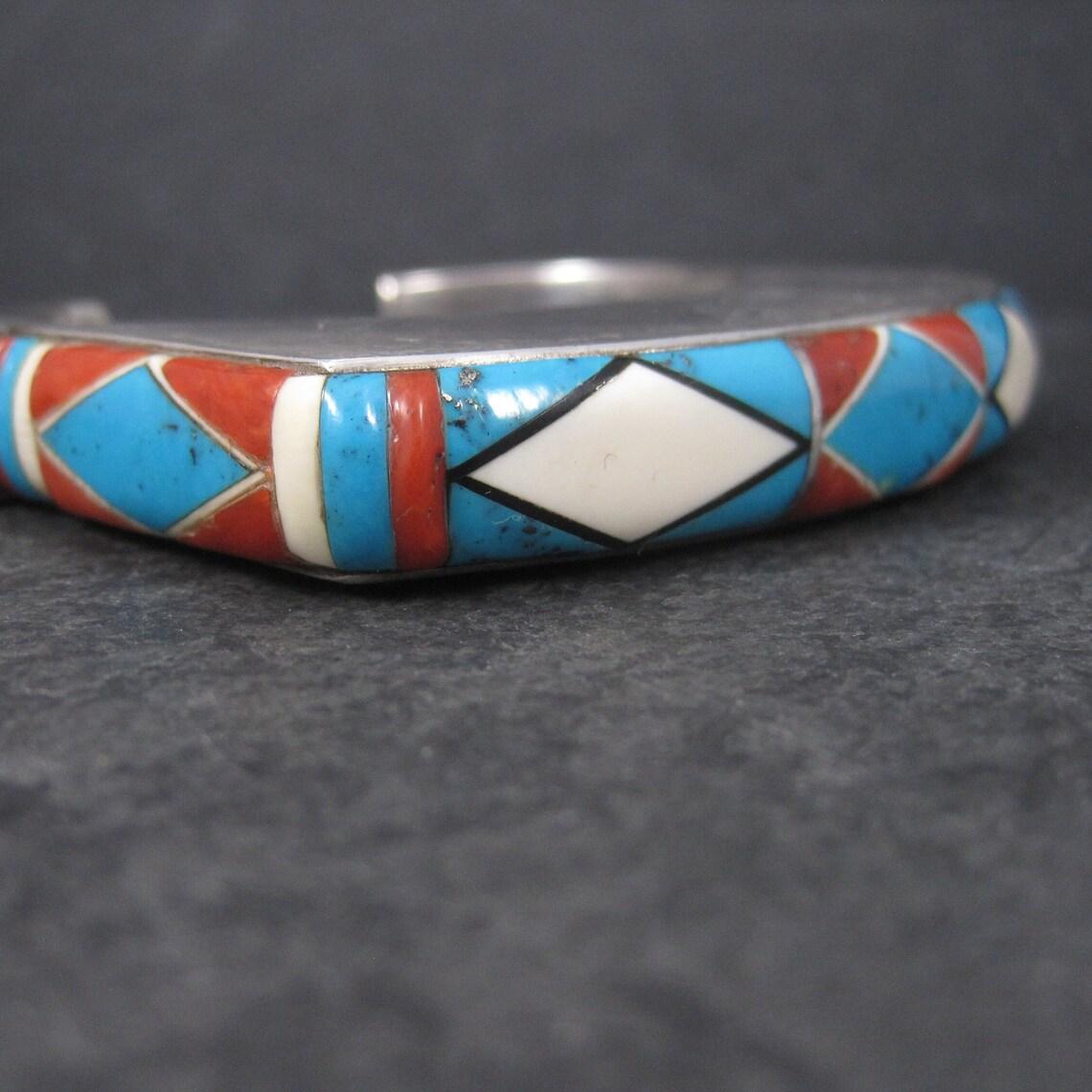 This gorgeous vintage cuff bracelet features gemstone inlay in red, white and blue with just a touch of black jet.
This piece is heavy, stunning and huge. Definitely not a bracelet for the faint of heart.

The face of this bracelet measures 1/2 of
