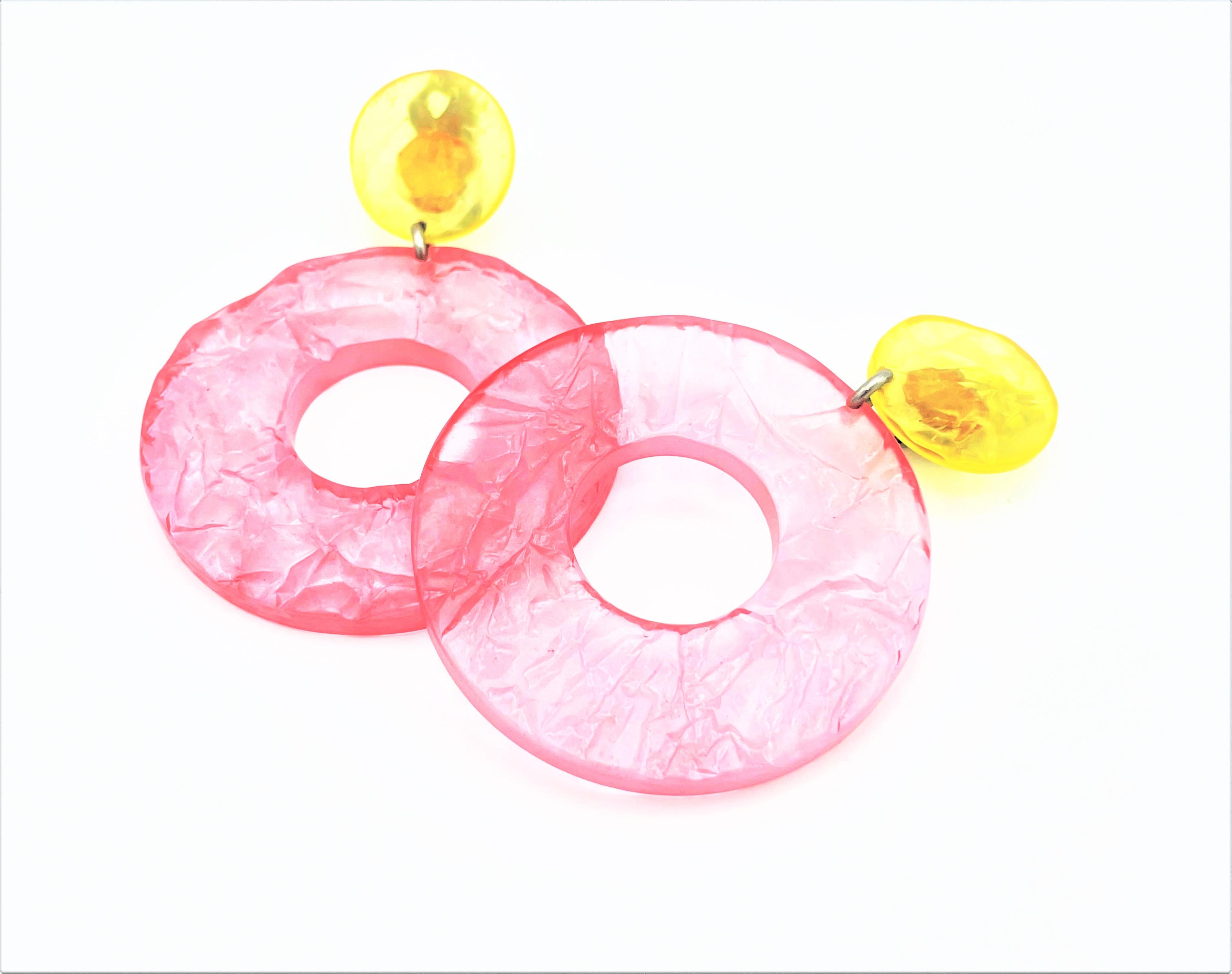 Enorme pendiente de clip decorativo veraniego procedente de Italia alrededor de  2000. Consta de una parte amarilla y un círculo de color rosa.   
Medidas: Largo total 9 cm, ancho 6,4 cm, fondo 0,5 cm. La parte amarilla de 2,5 de diámetro,  el