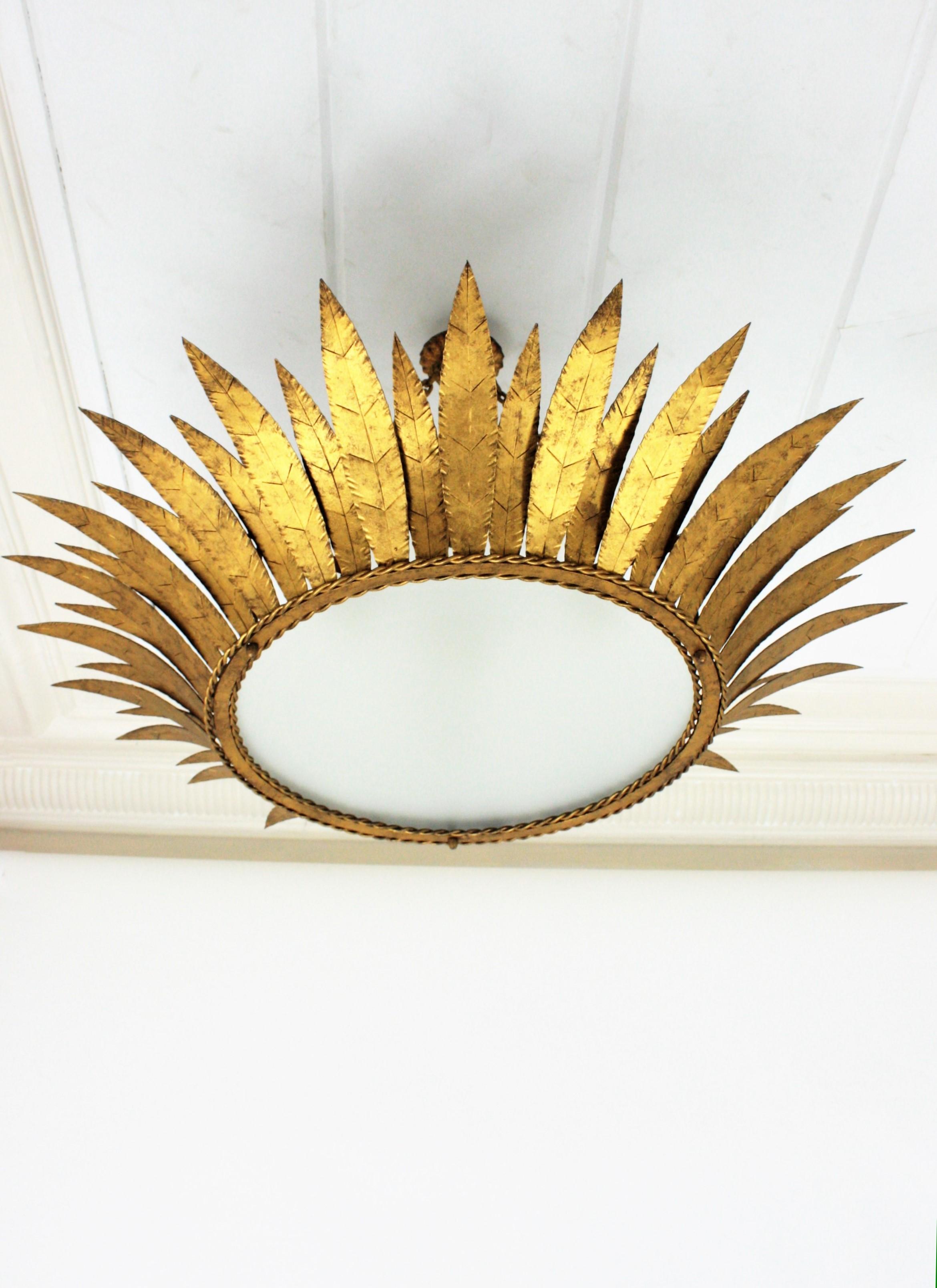 Monumental Sunburst crown chandelier / ceiling light fixture, Spain, 1950s
This outstanding crown ceiling lamp features a leafed frame in sunburst disposition surrounding a central frosted glass panel to difusse the light.
It can be placed flush