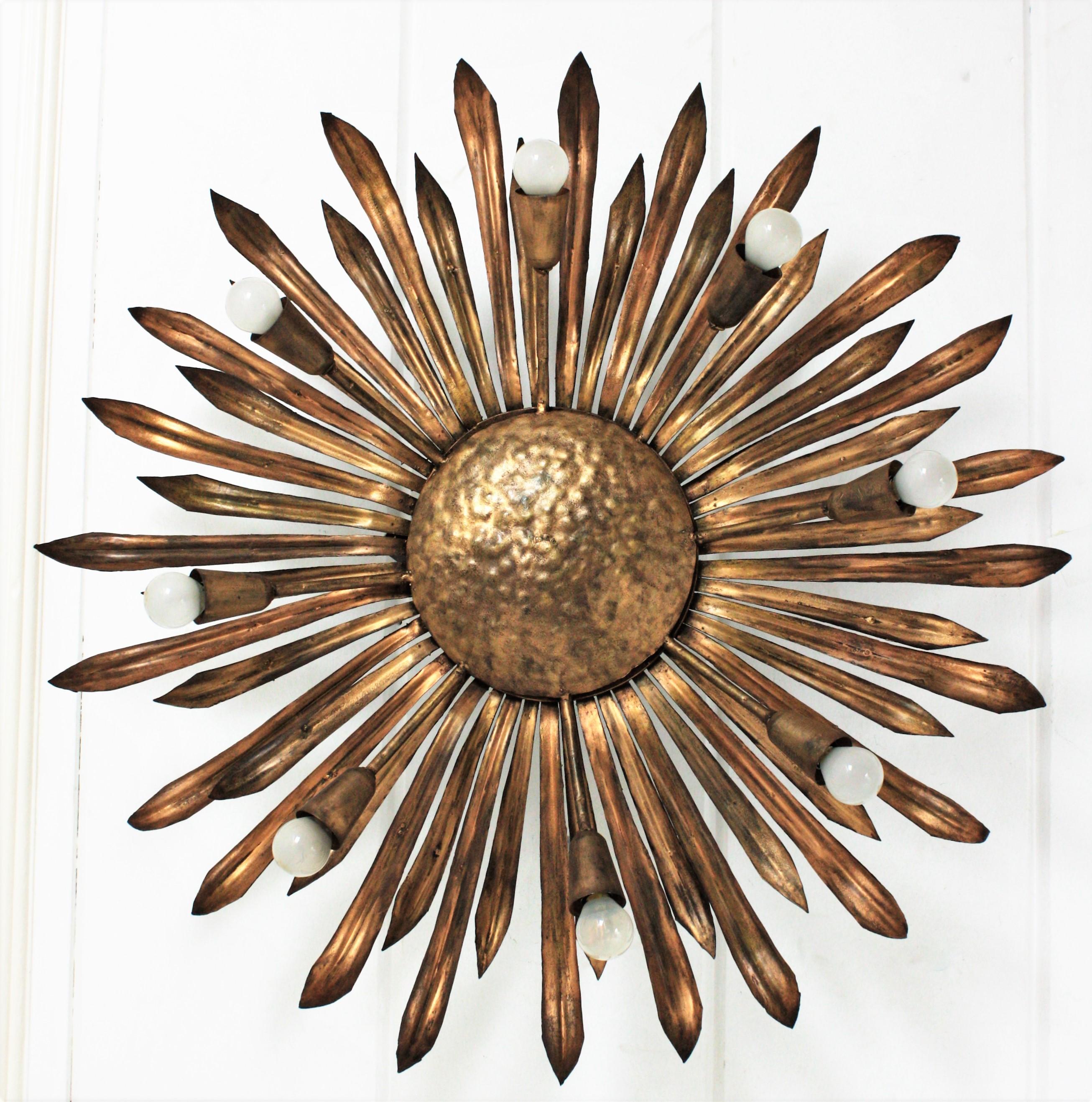Sunburst leafed Flush Mount / chandelier in Gilt Iron. Spain, 1960s
Outstanding eight-light gilt metal sunburst or floral ceiling light fixture with alternating petals or leaves. Gilt patinated finish in bronze and golden tones.
Manufactured at