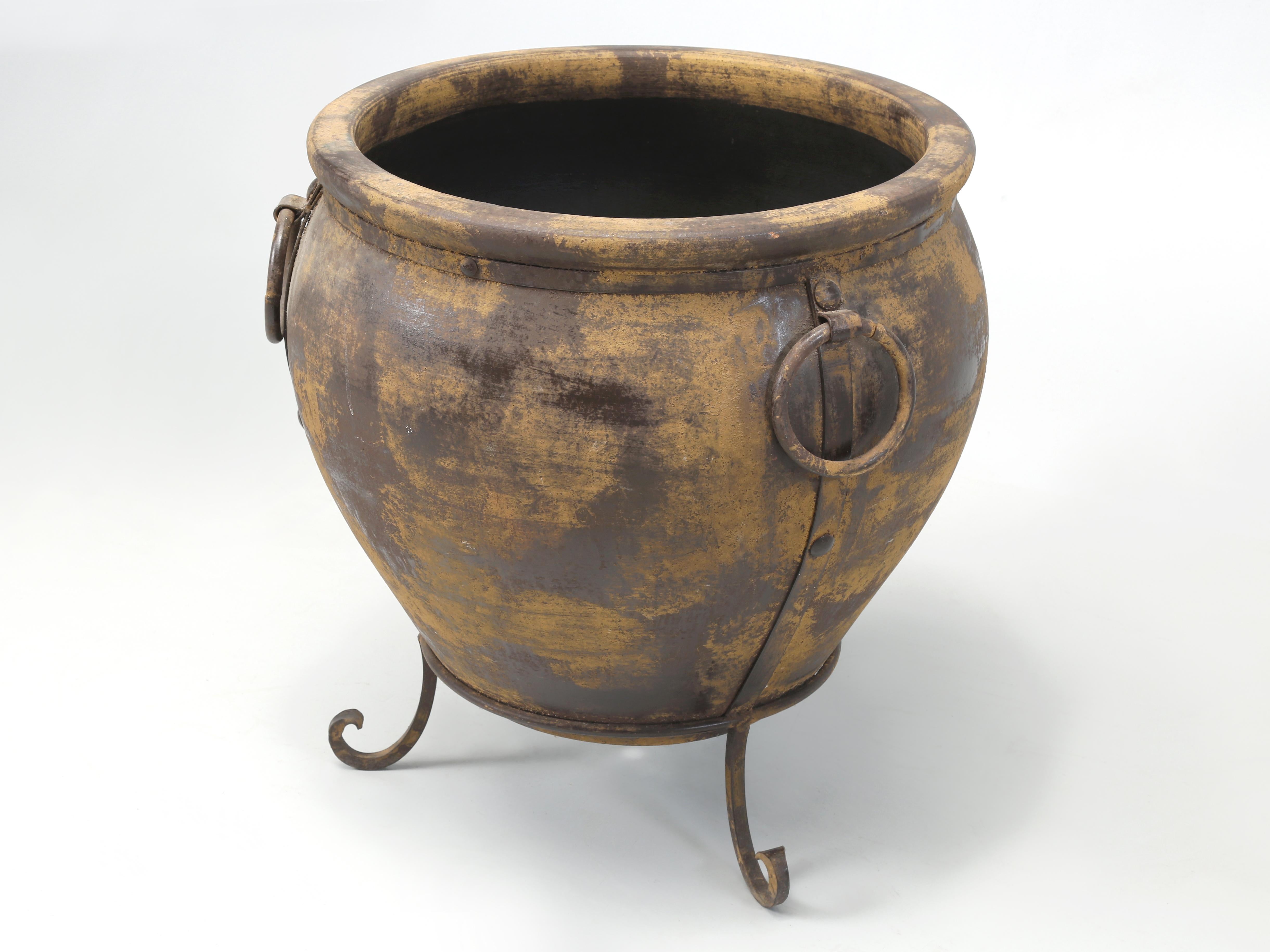 Huge Indoor or Outdoor Garden Planter made from Terracotta and resting on a wrought iron base. The pot has Survived several Winters, but I certainly would cover it up. The Planter is large enough to hold a decent size tree as you can see in the last