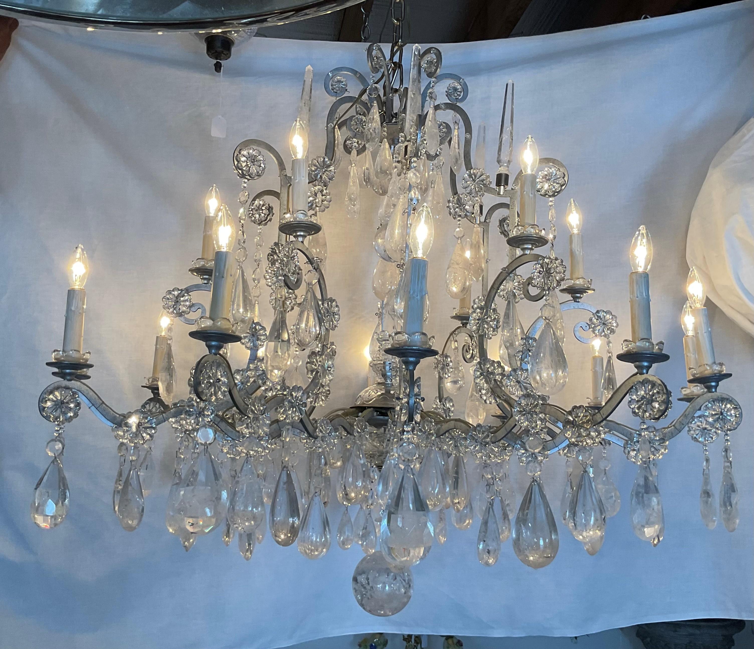 Make a grand statement with this stunning crystal chandelier. Featuring an ornate metal frame with scrolling arms, this chandelier is adorned with cascading crystal prisms and drops that beautifully reflect light for a sparkling effect. With 12
