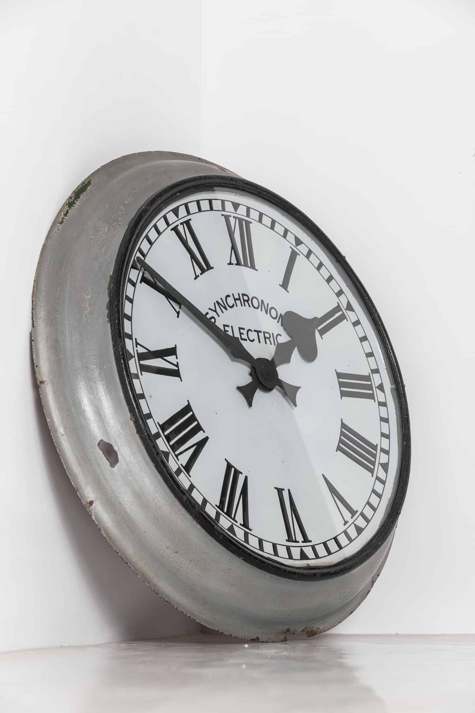 Huge enamel wall clock made in England by Synchronome. c.1930.

All in one design made entirely of enameled steel with later grey/silver paint, and dial bearing the makers mark and Roman numerals. Some chipping to the outside edge as to be
