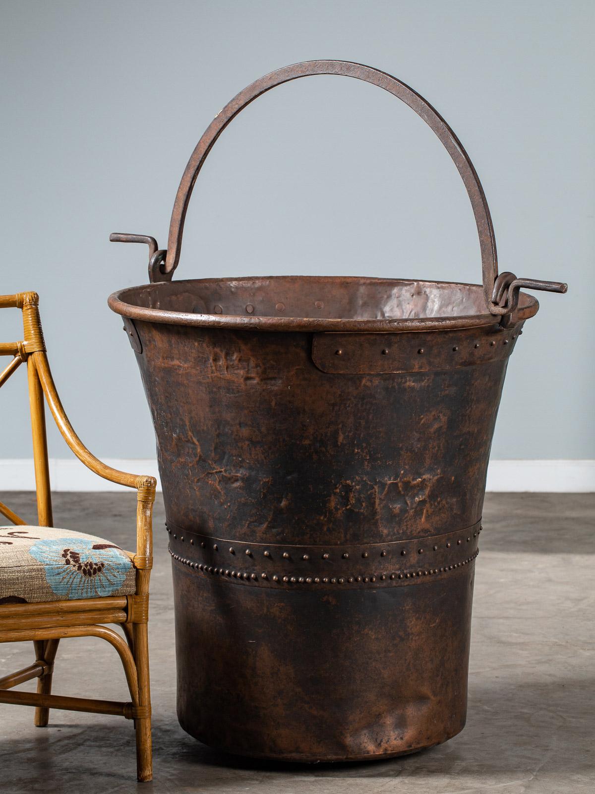 An enormous copper chocolate vat from Switzerland circa 1890 with the original iron handle. Made from sheets of copper riveted together this huge vat was used in the large scale production of chocolate. Entirely circular with a rounded base the