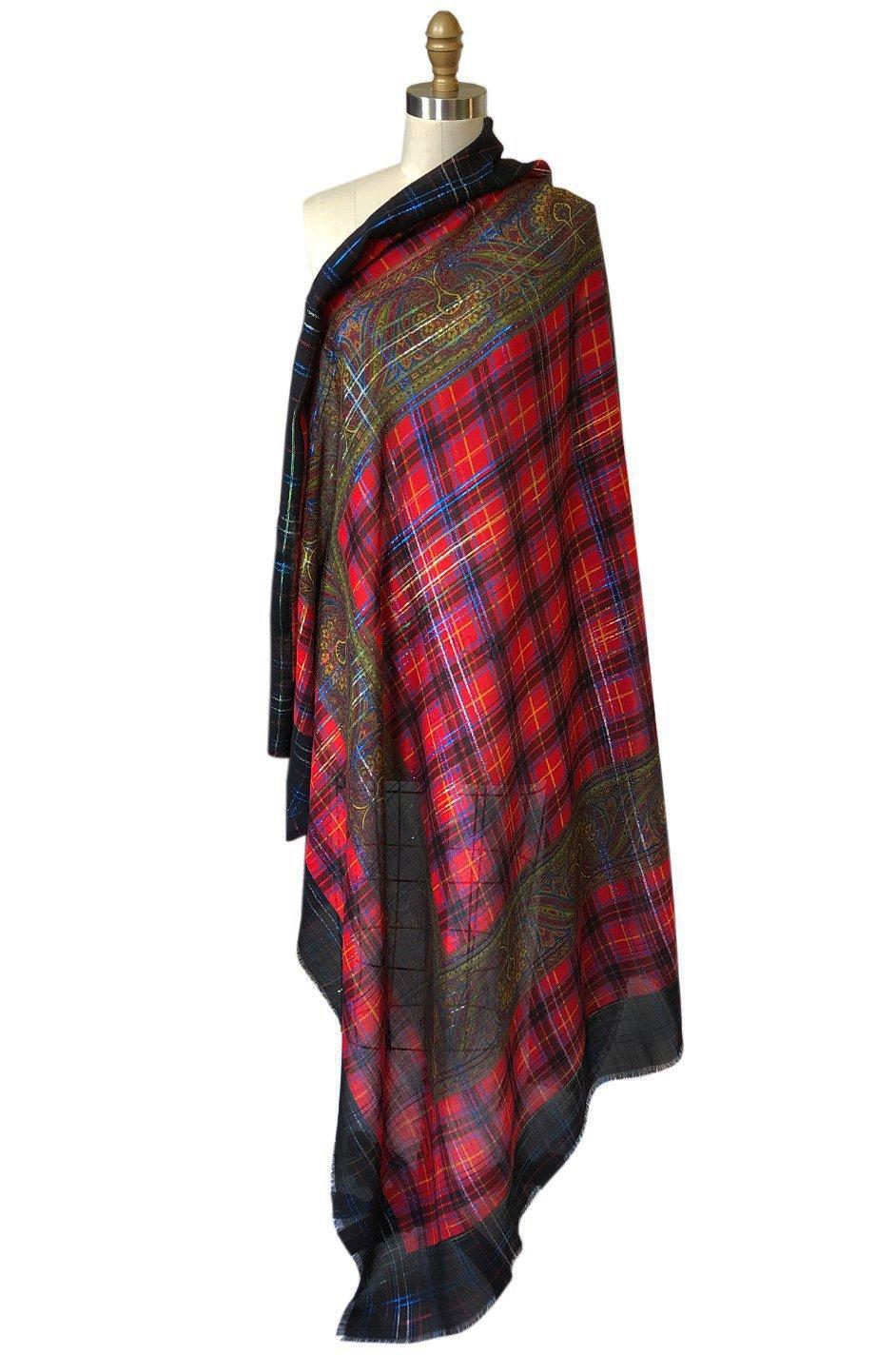 Gorgeous and absolutely huge, this Yves Saint Laurent plaid scarf is a mix of a bright red with a jet black border that is overlaid with shots of metallic blue and gold thread. The plaid surrounds a intricate paisley printed inner border that is