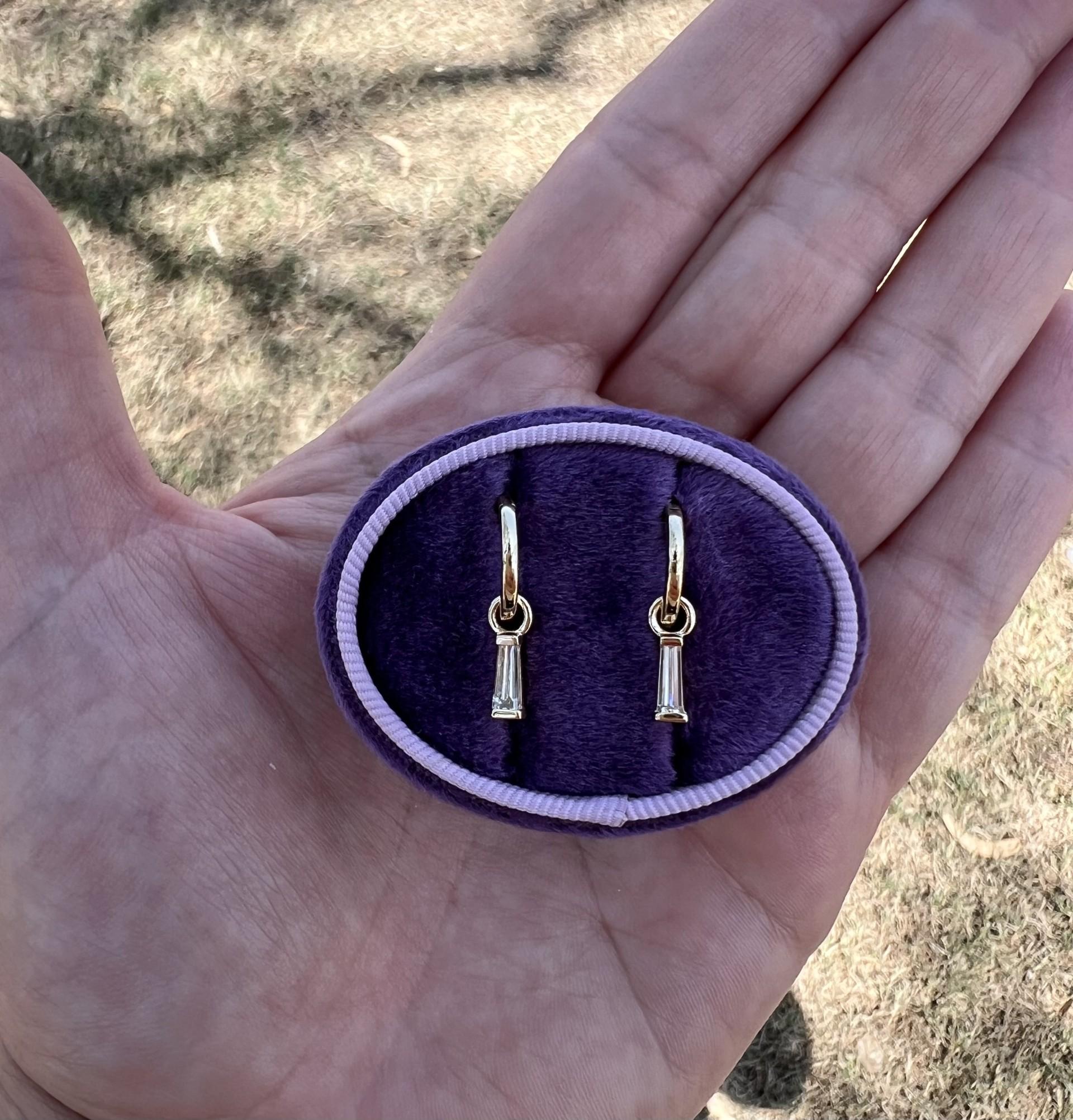 Introducing our exquisite 14k yellow gold diamond huggie hoop earrings, a perfect blend of elegance and versatility. These hoops feature stunning tapered baguette diamonds, totaling .59 carats, that dangle delicately, catching the light with every