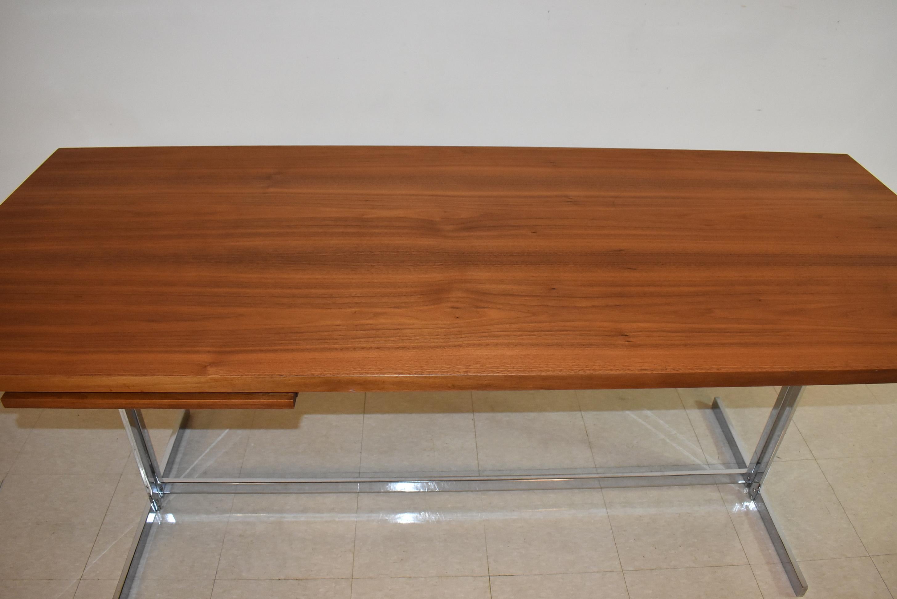 Questa scrivania Hugh Acton in teak e cromo ha una base a cavalletto cromata. Il piano della scrivania in teak è lungo 76