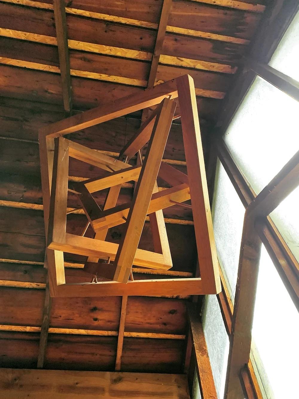 A unique hanging sculpture consisting of 4 interlocking squares set at random angles held in place with dowels. This piece was bought from mid century modern designer Hugh Acton's estate where it hung from loft beams in his barn (see photos). Acton
