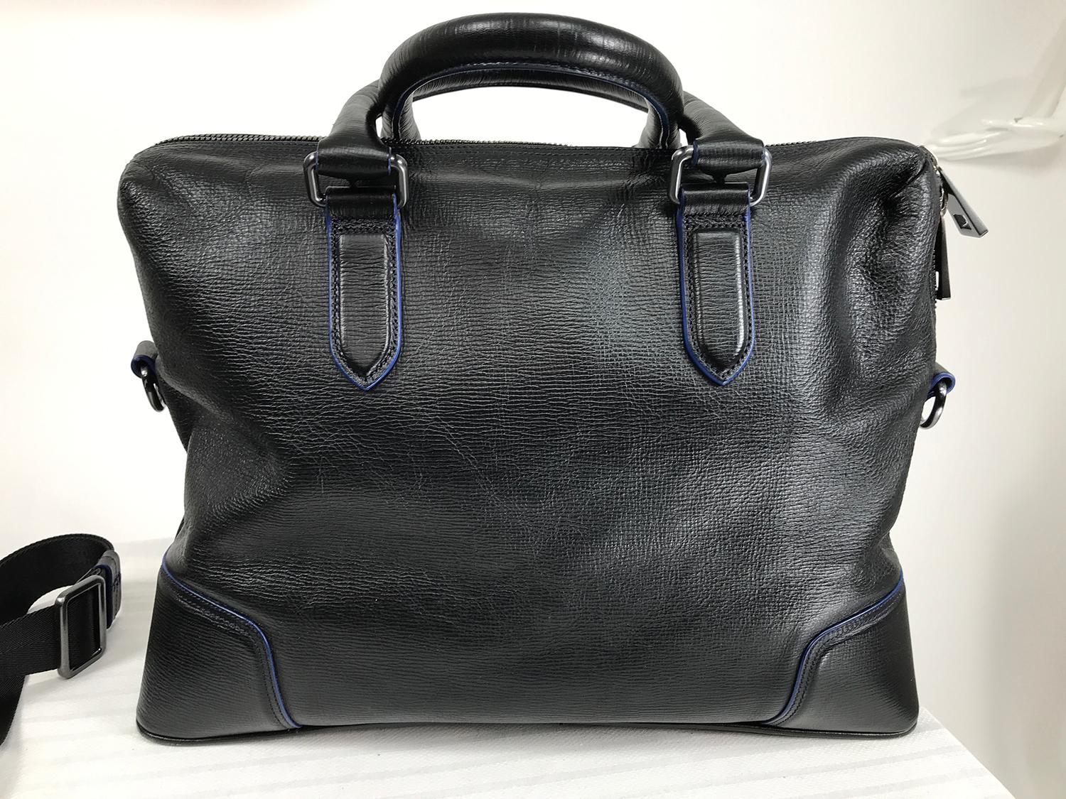 Hugo Boss black & blue leather business bag, carry on or shoulder bag. Soft black leather double handle bag is trimmed with bright blue welt cord. Curved top back closes with a chunky zipper, gunmetal hardware. Removable shoulder strap is