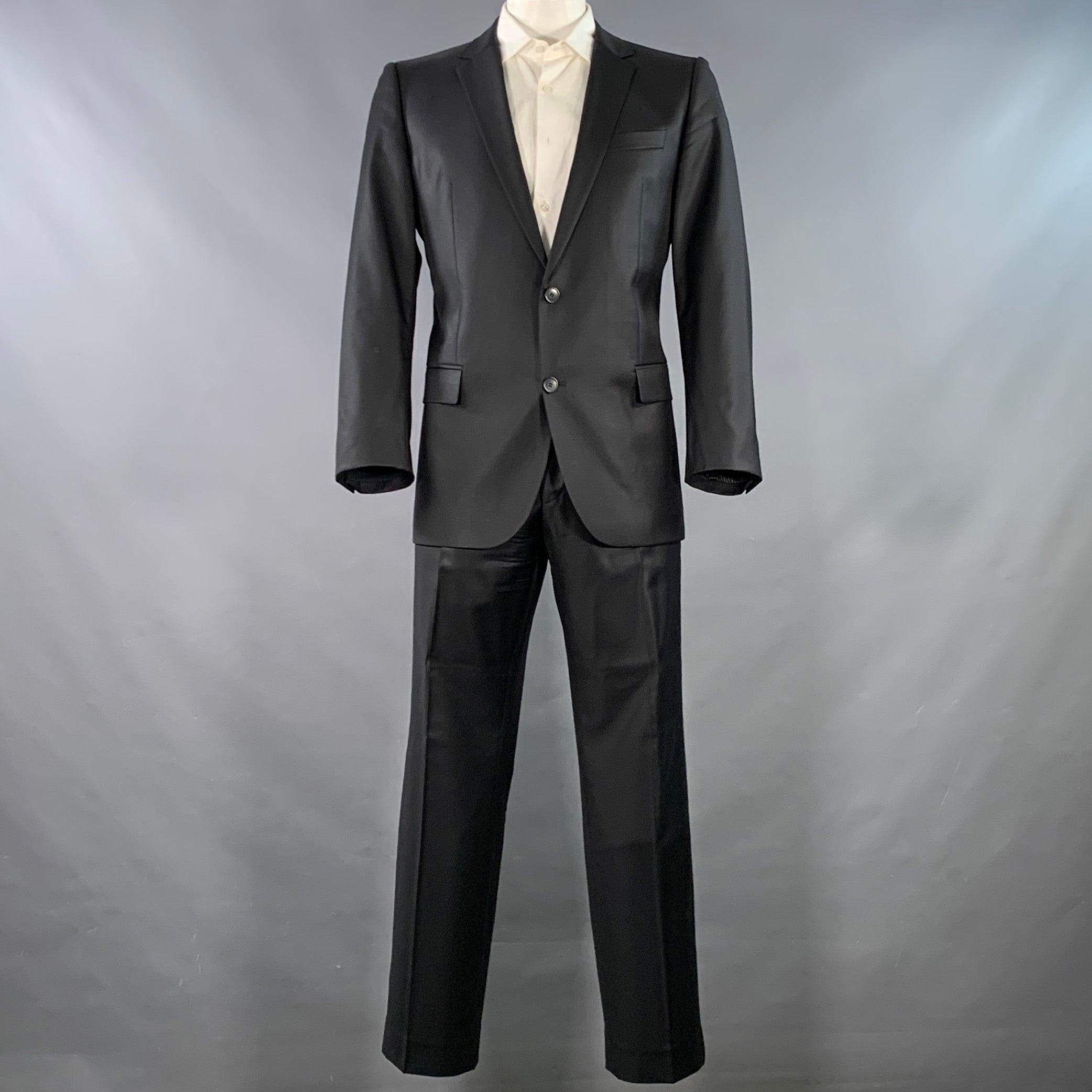 HUGO by HUGO BOSS Anzug
in schwarzem Wollzwirn mit vollem Futter und umfasst einen einreihigen Sportmantel mit doppelter Knopfleiste und Revers sowie eine passende Hose mit flacher Vorderseite in sehr gutem, gebrauchtem Zustand. 

Markiert:   IT 54