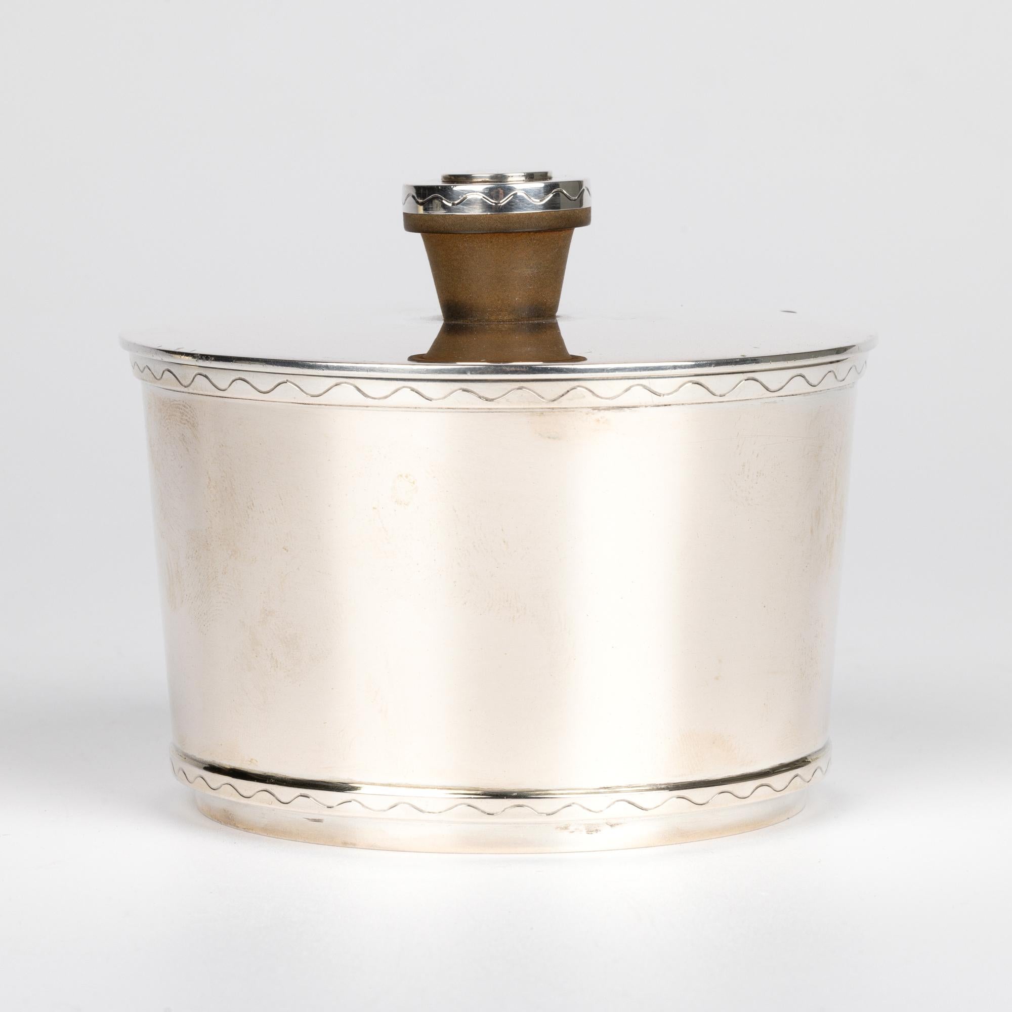 Una zuccheriera con coperchio in argento della metà del secolo, molto elegante e di qualità, realizzata dal rinomato produttore svedese Hugo Grün & Co. e datata 1948. La ciotola di forma cilindrica rotonda è sollevata su un bordo con piede rotondo e