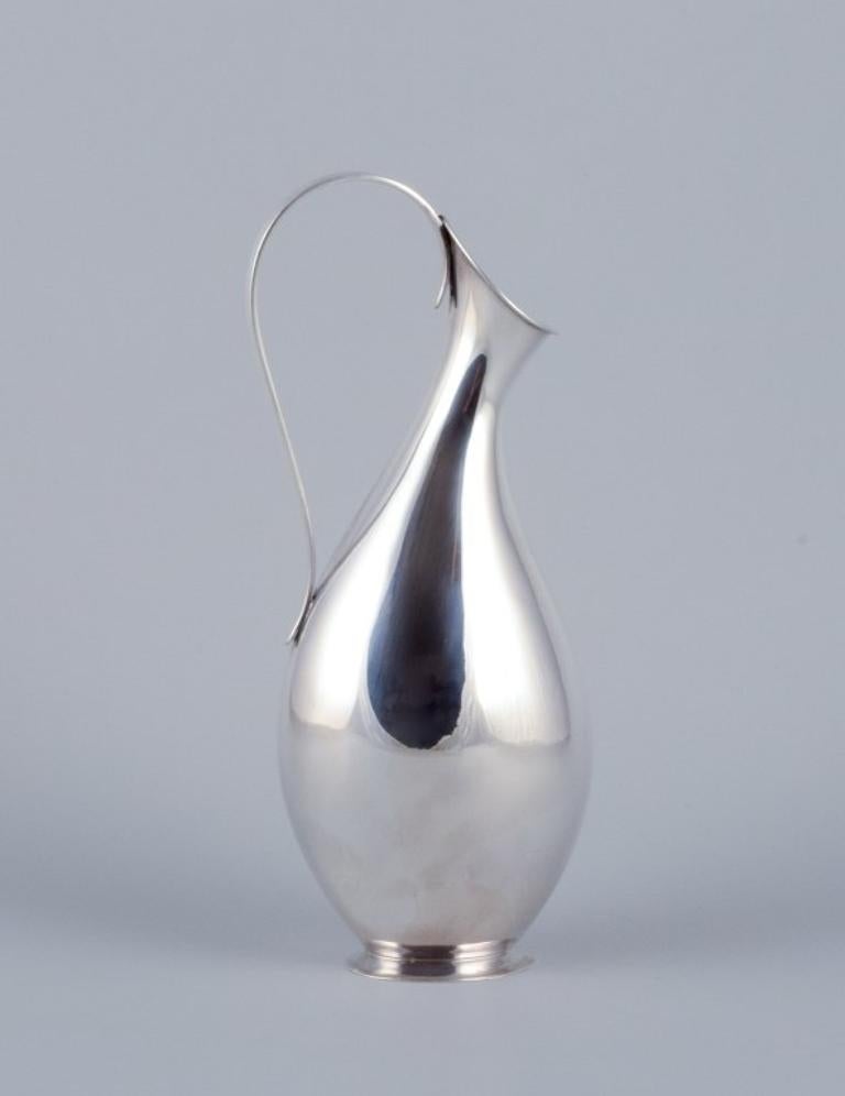 Hugo Grün, Danish silversmith. Modernist pitcher in sterling silver in an organic and sleek design.
Mid-20th century.
Hallmarked.
In excellent condition.
Dimensions: Height 22.5 cm including handle x Diameter 9.5 cm.
