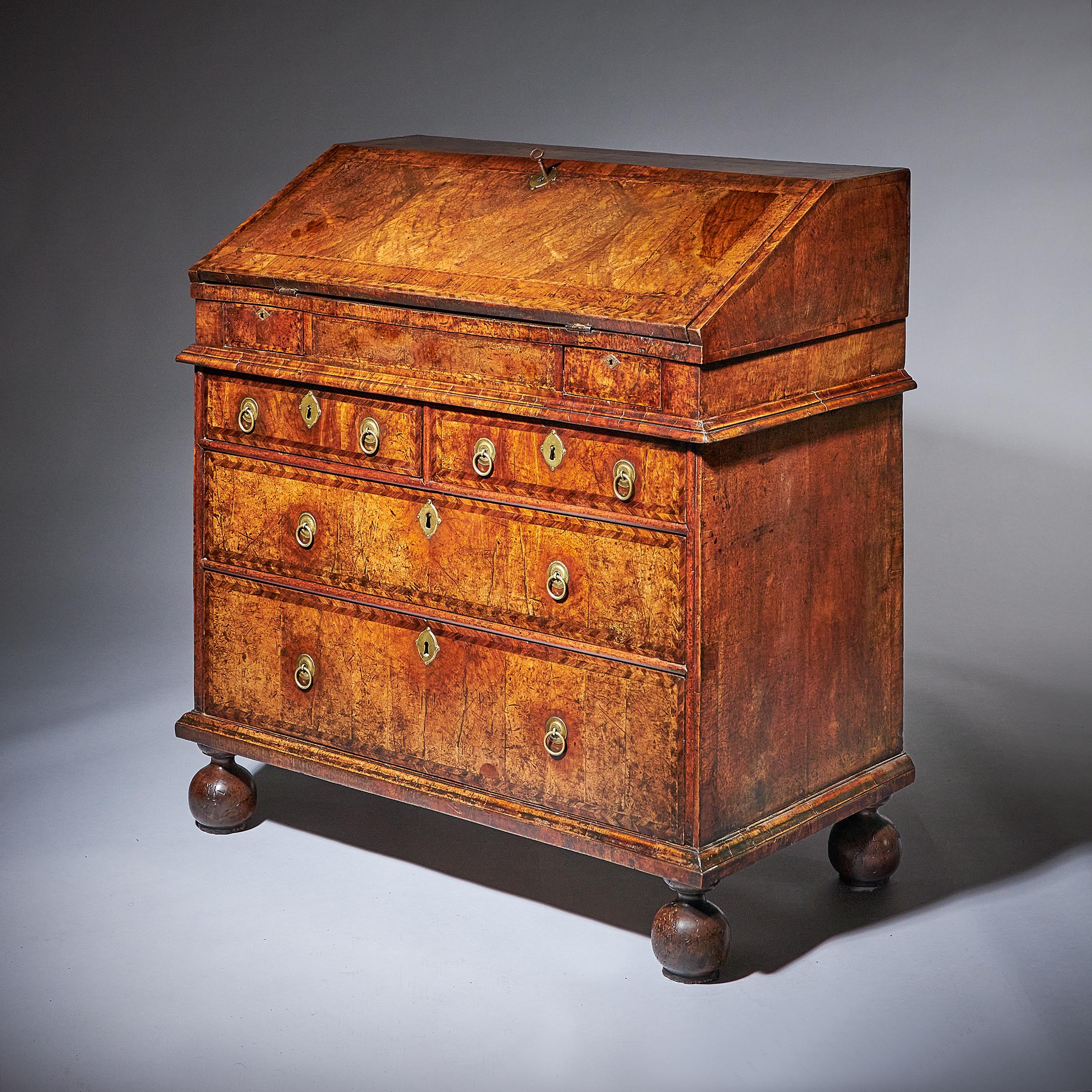 A rare and Important late 17th century Charles II / William and Mary figured walnut two-piece bureau circa 1680, England. 

The cross and double feather-banded top is veneered in book-matched figured walnut over a book-matched figured walnut