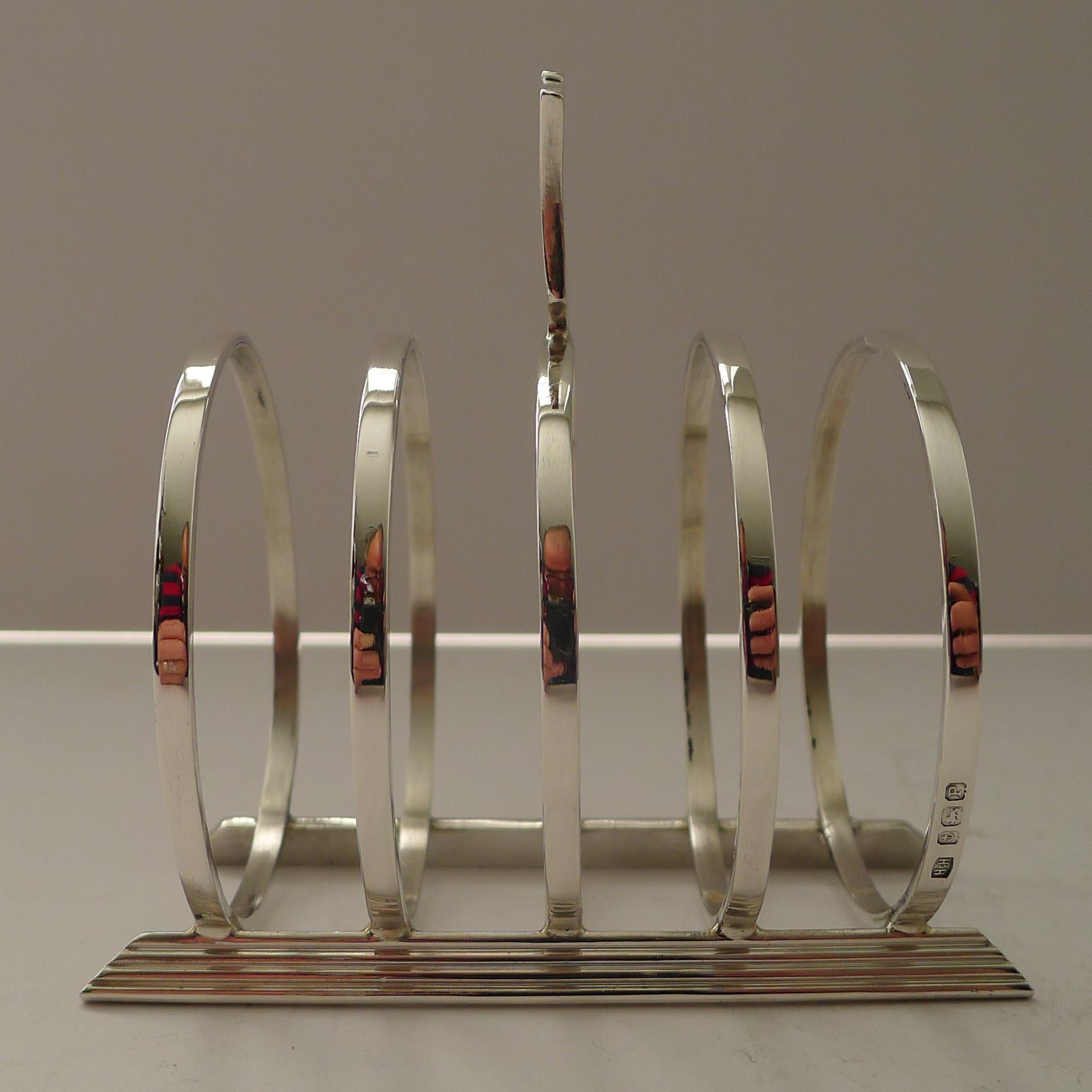 Un perfecto y elegante tostador de plata inglesa maciza con un sorprendente e inusual diseño Art Decó, fabricado por la orfebre Hukin and Heath.

La plata tiene el matasellos de Birmingham de 1939 y la marca del fabricante 
