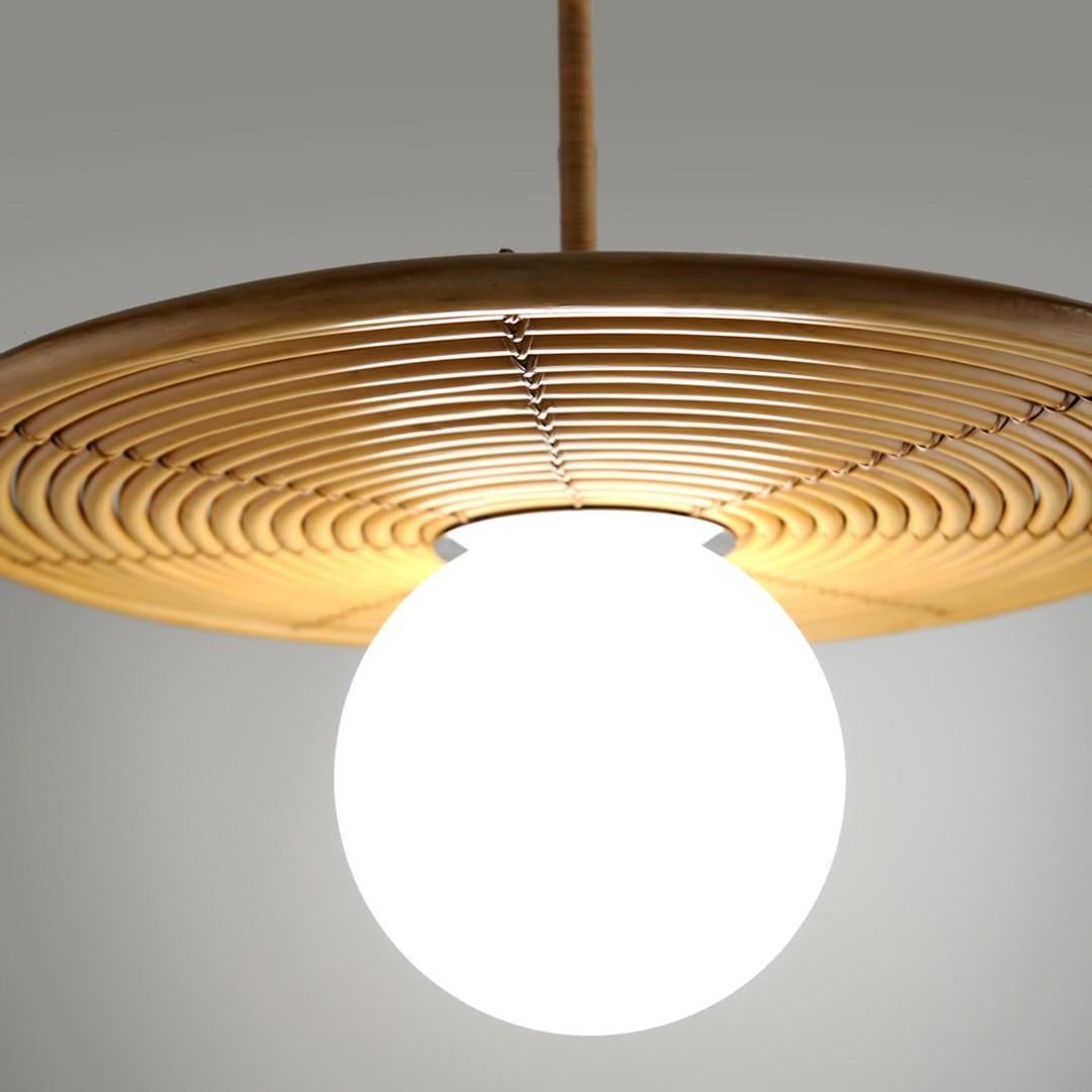 Martyn Lawrence Bullard for Corbett Lighting
A series of nested natural rattan rings create an elegant disc shade accented by a contrasting stainless steel center plate for a balanced modern yet organic aesthetic. 
The opal white glass globe creates