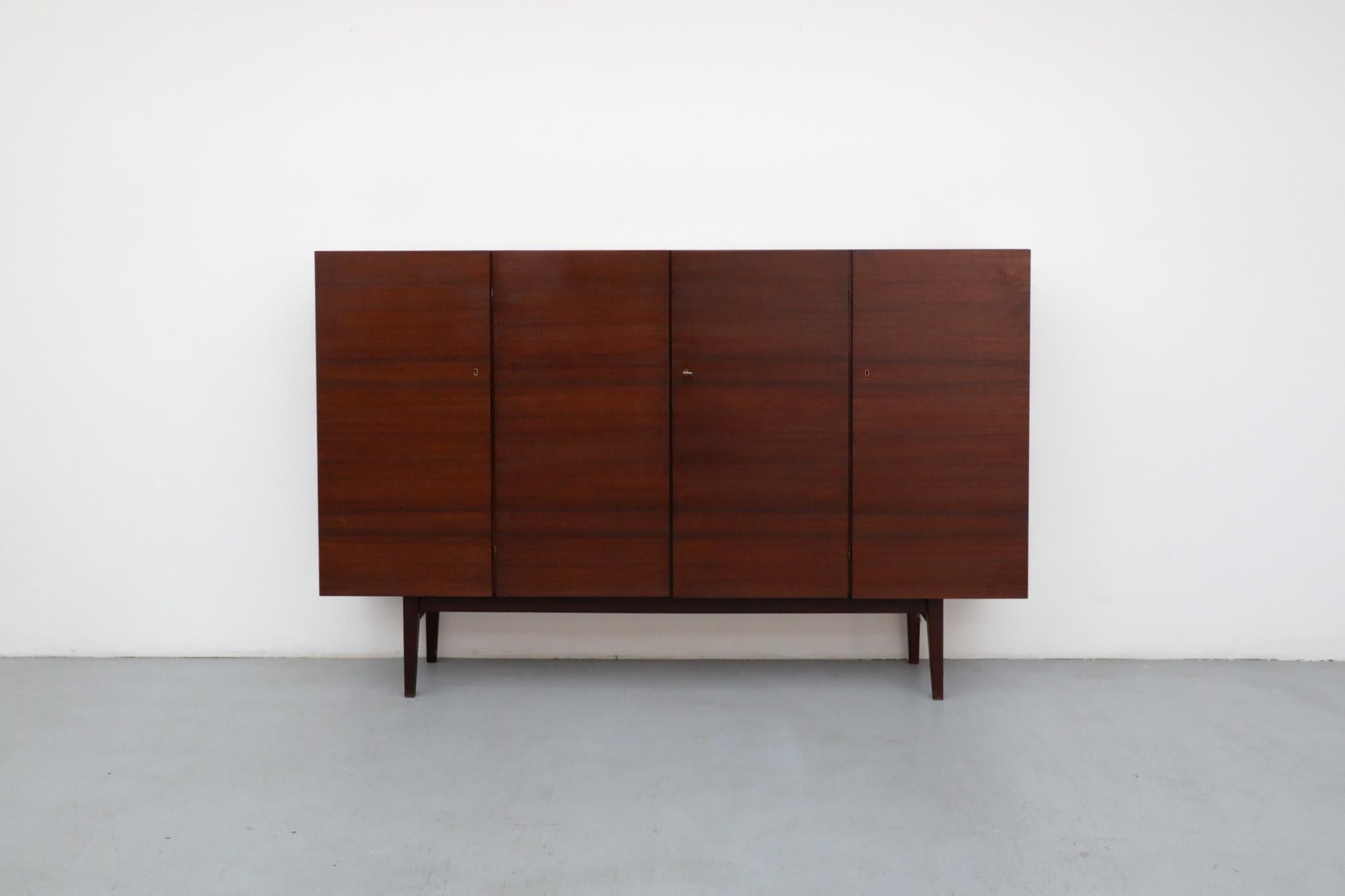 Credenza di metà secolo, grande e alta in teak scuro con interni biondi a contrasto di Hulmefa, anni '60. Le porte si aprono per rivelare scaffali e un piccolo wet bar con schienale a specchio. Leggermente rifinito in legno, il pezzo è in buone