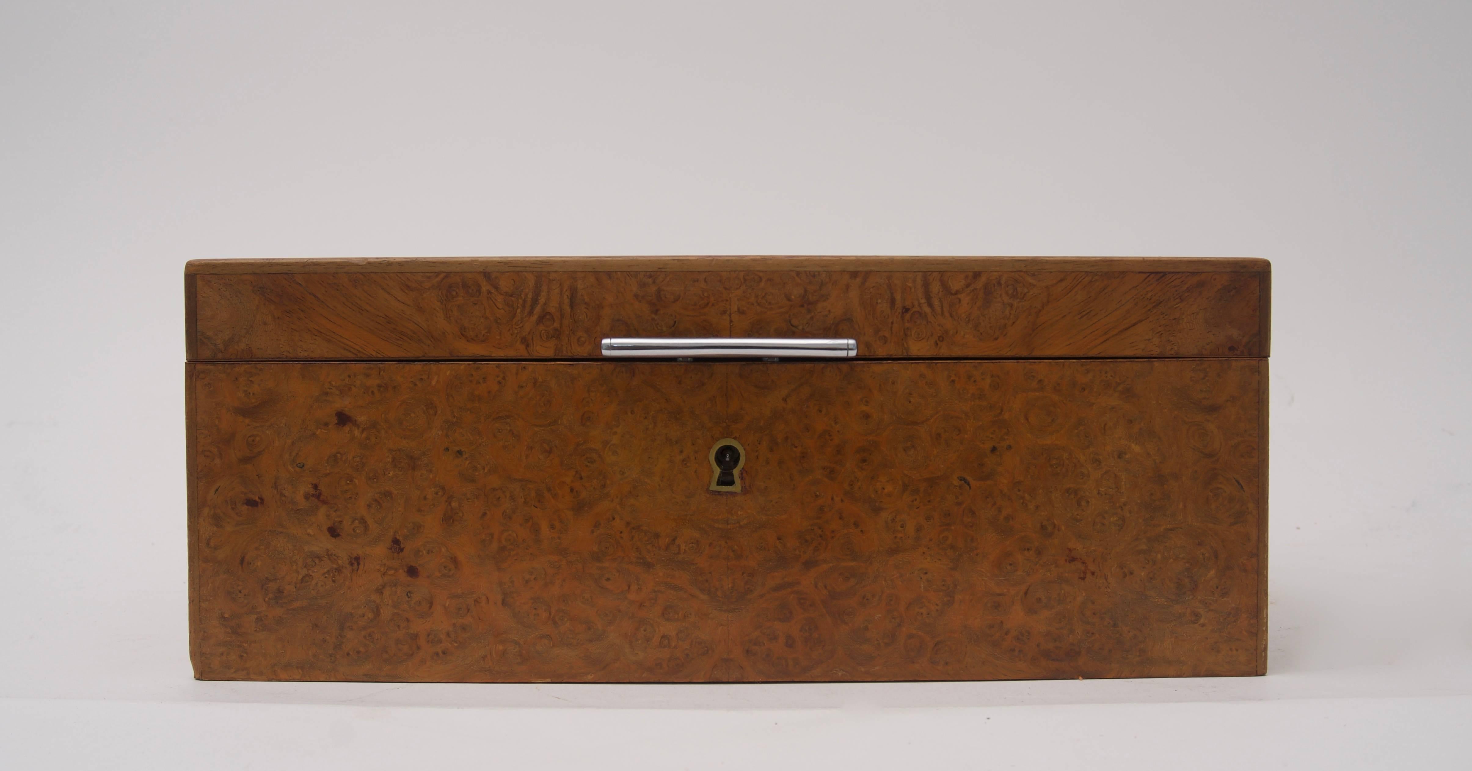 This stylish Dunhill humidor is fabricated in burl wood veneers, white glass and chrome trim. The piece was retailed in the pair branch of the Dunhill shops at 15 Rue de la Paix and dates we think to the 1960s or 1970s. The burl wood has a warm