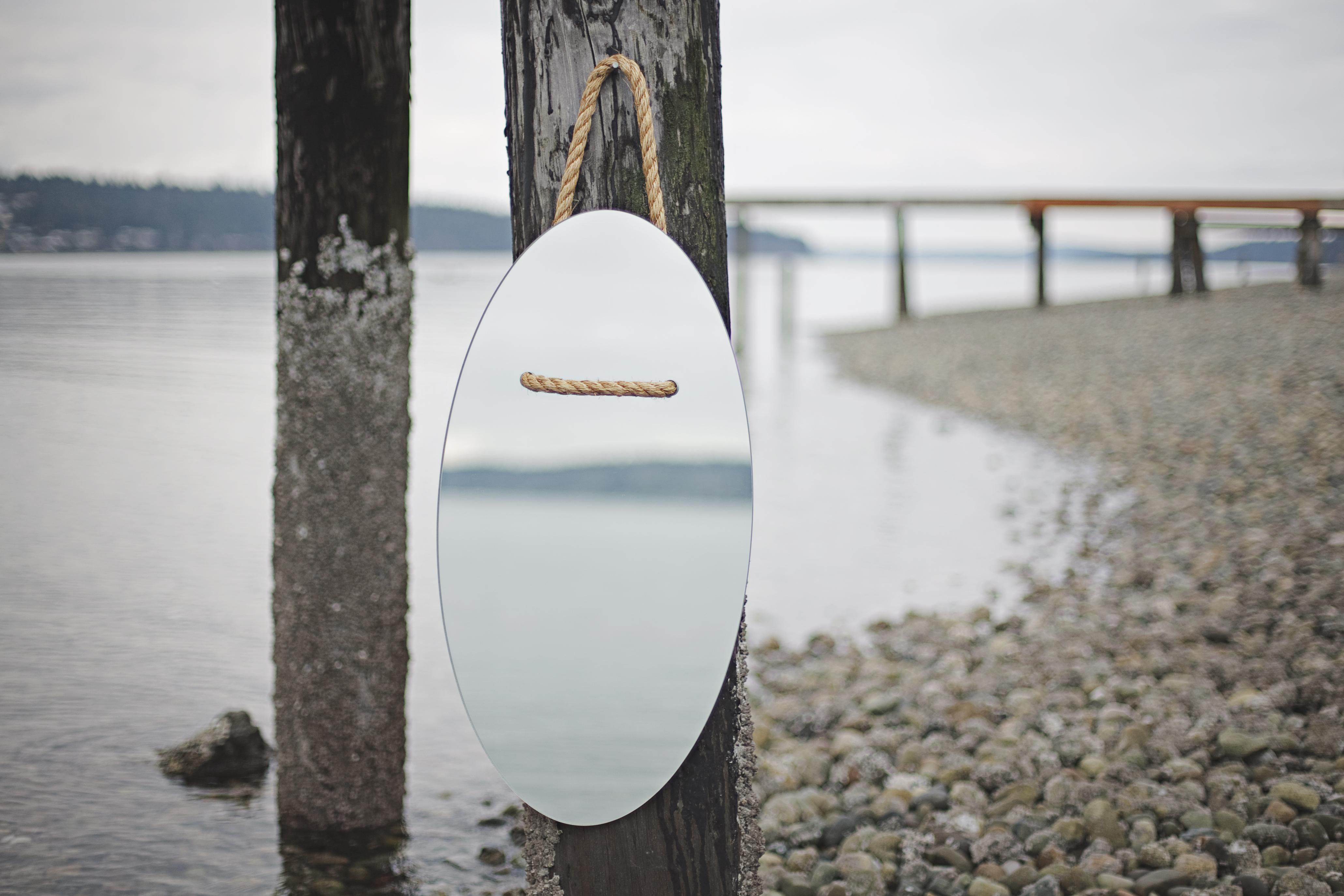 An oval shaped waterjet cut mirror threaded and hung by manila rope.

Dimensions:
Overall Height: 39 in / 99.1 cm
Width: 16 in / 40.6 cm
Depth: 0.25 in / 0.6 cm
Rope Dia: 0.75 / 1.9 cm

Custom sizes/shapes available. 

Material:
Mirrored clear