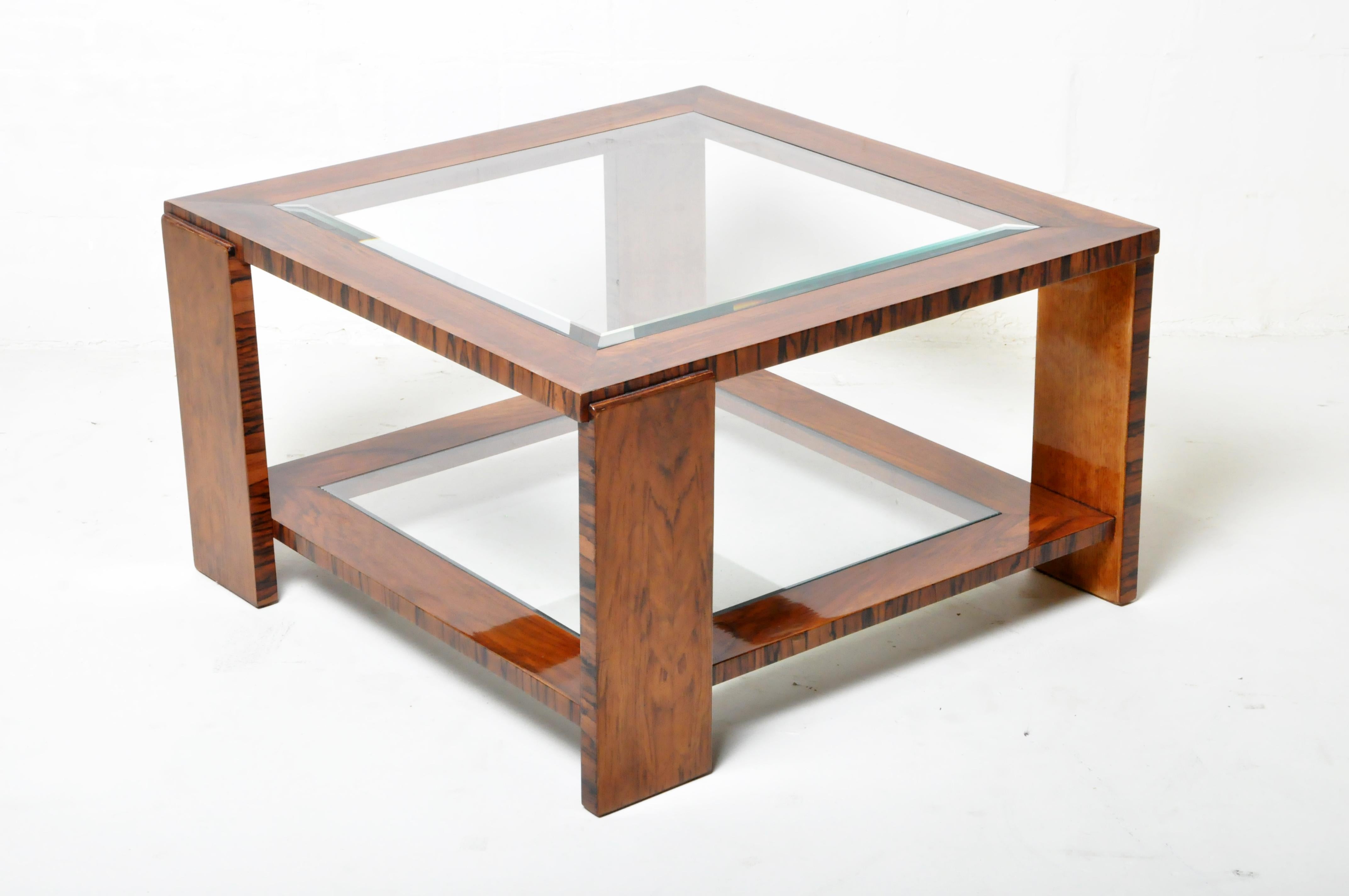 This vintage Art Deco coffee table is from Budapest, Hungary, and was made from walnut and glass, c. 1940. The table features a glass top inset in a wide walnut veneer frame. The piece also features a glass shelve at the bottom for display. Wear