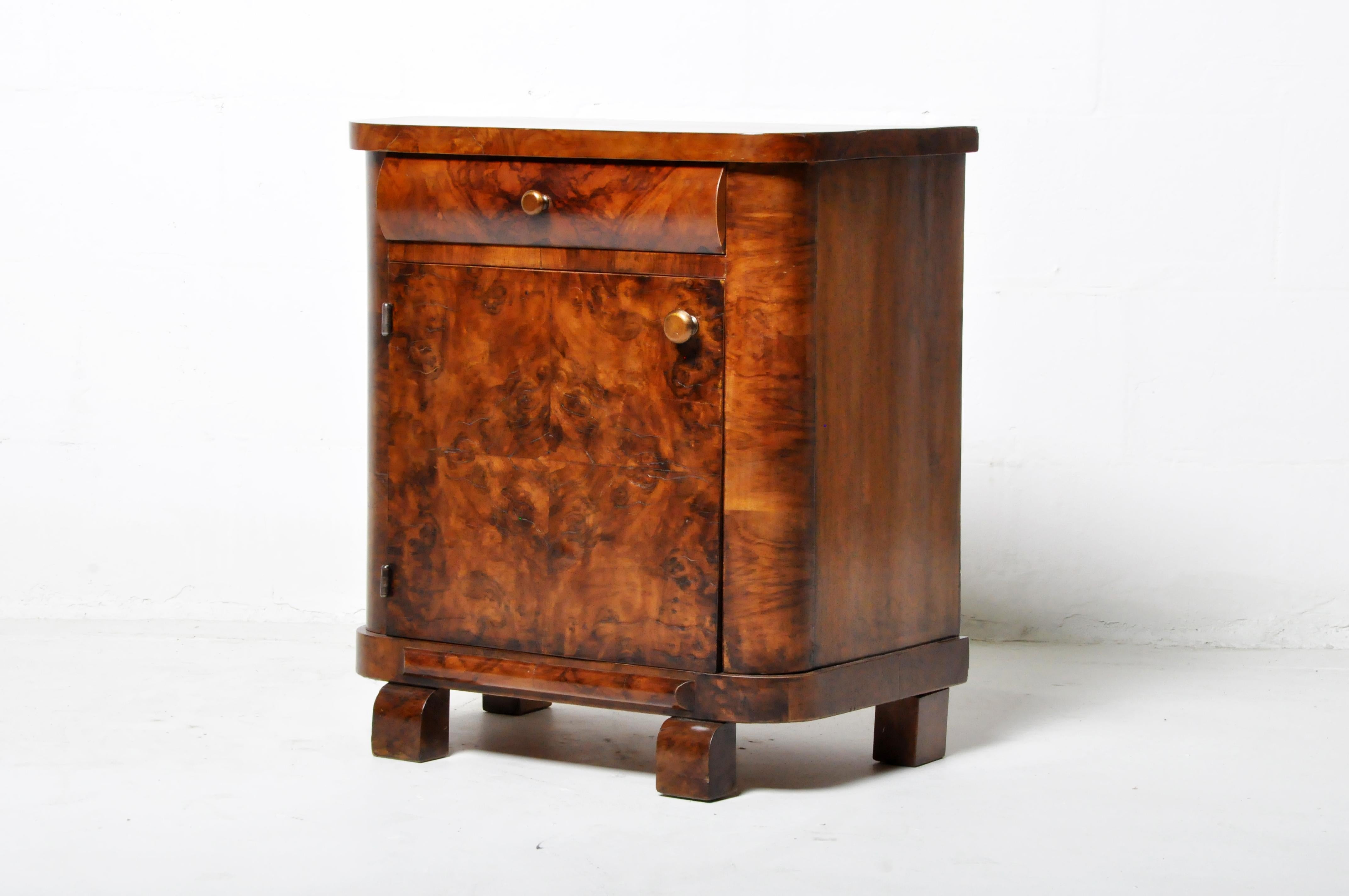 This beautiful Art Deco side chest is from Budapest, Hungary, and was made from walnut veneer, c. 1940. The side chest features a drawer, a door that opens up for storage, and a beautifully aged patina. Wear consistent with age and use; patina is