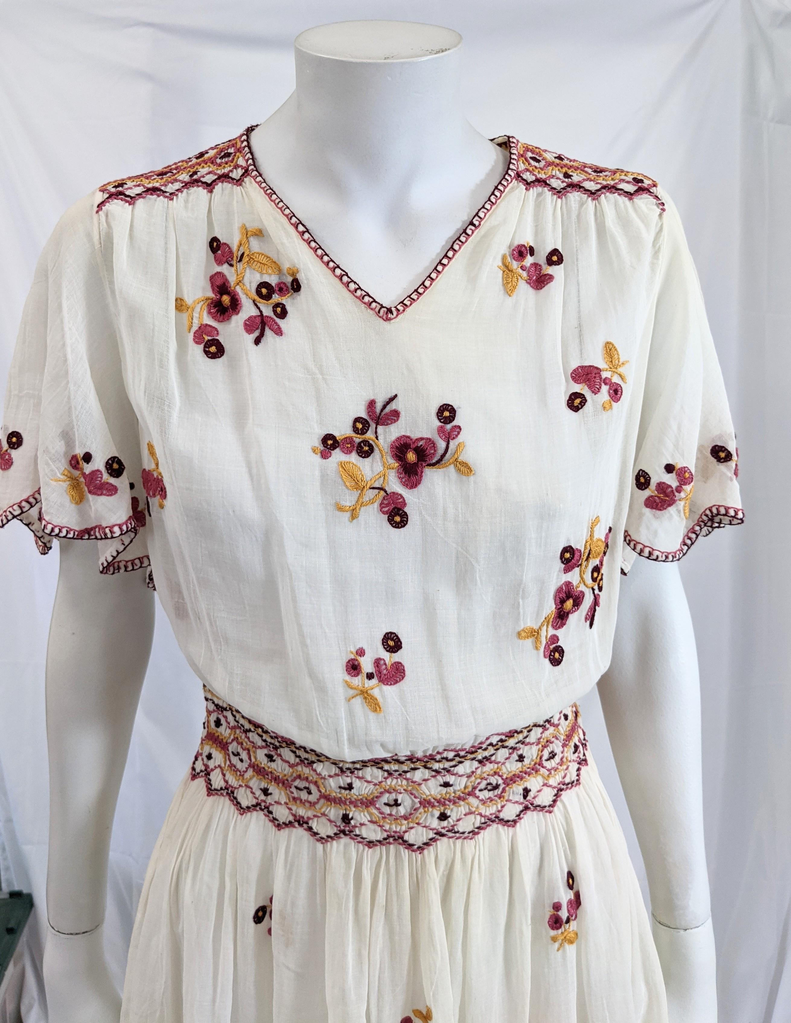 Charming Hungarian Embroidered Cotton Batiste Dress with smocked detailing from the 1920's. Unusual cut with flutter sleeves (instead of gathered) and hand embroidered sprays in maroon, pink and gold. 
Small size dress pulls over head with a few