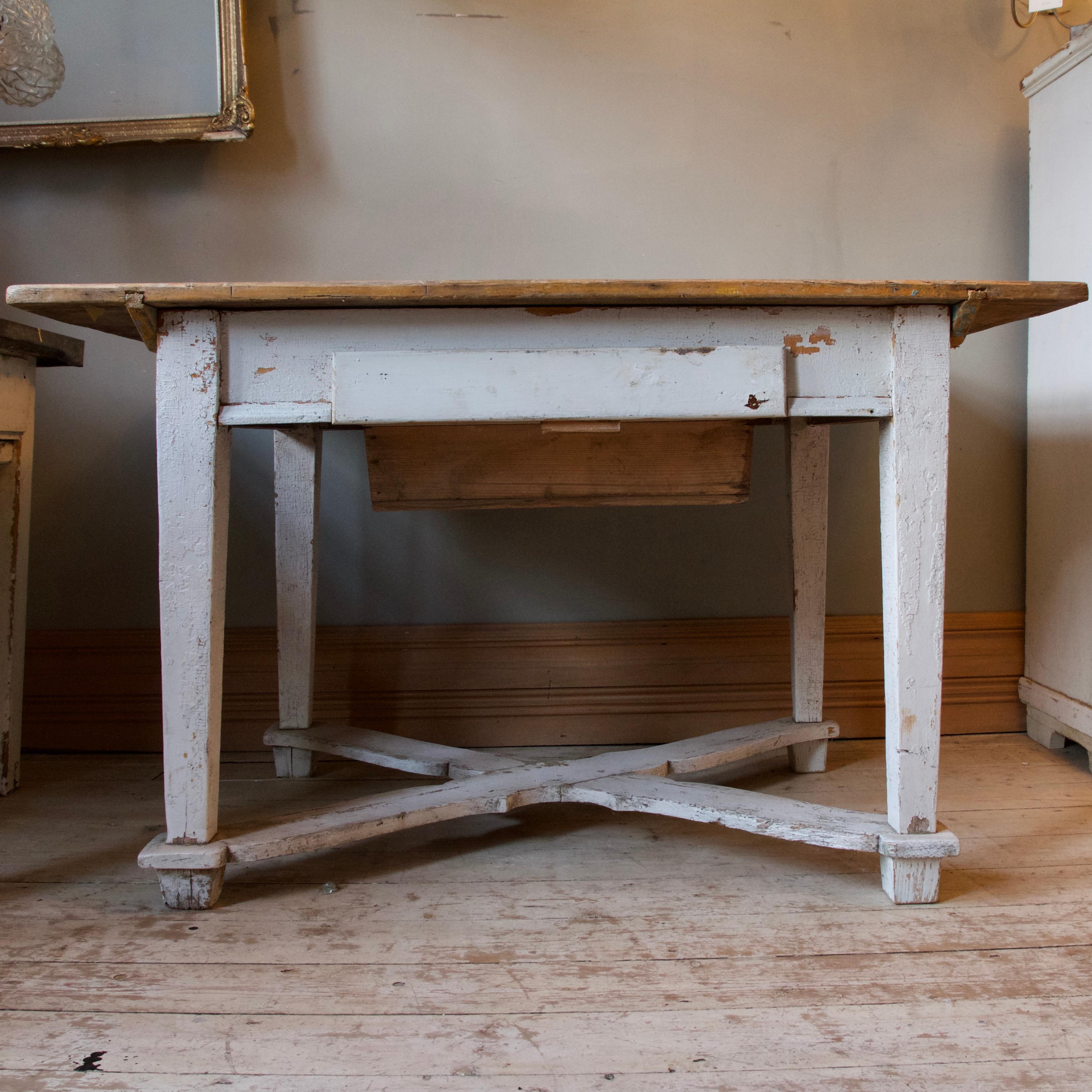 This charming table originates from Hungary. It has a naturally distressed finish which has been acquired through years of use. The tabletop has the remains of the original crackled green paint and the base retains the original white paint, this too