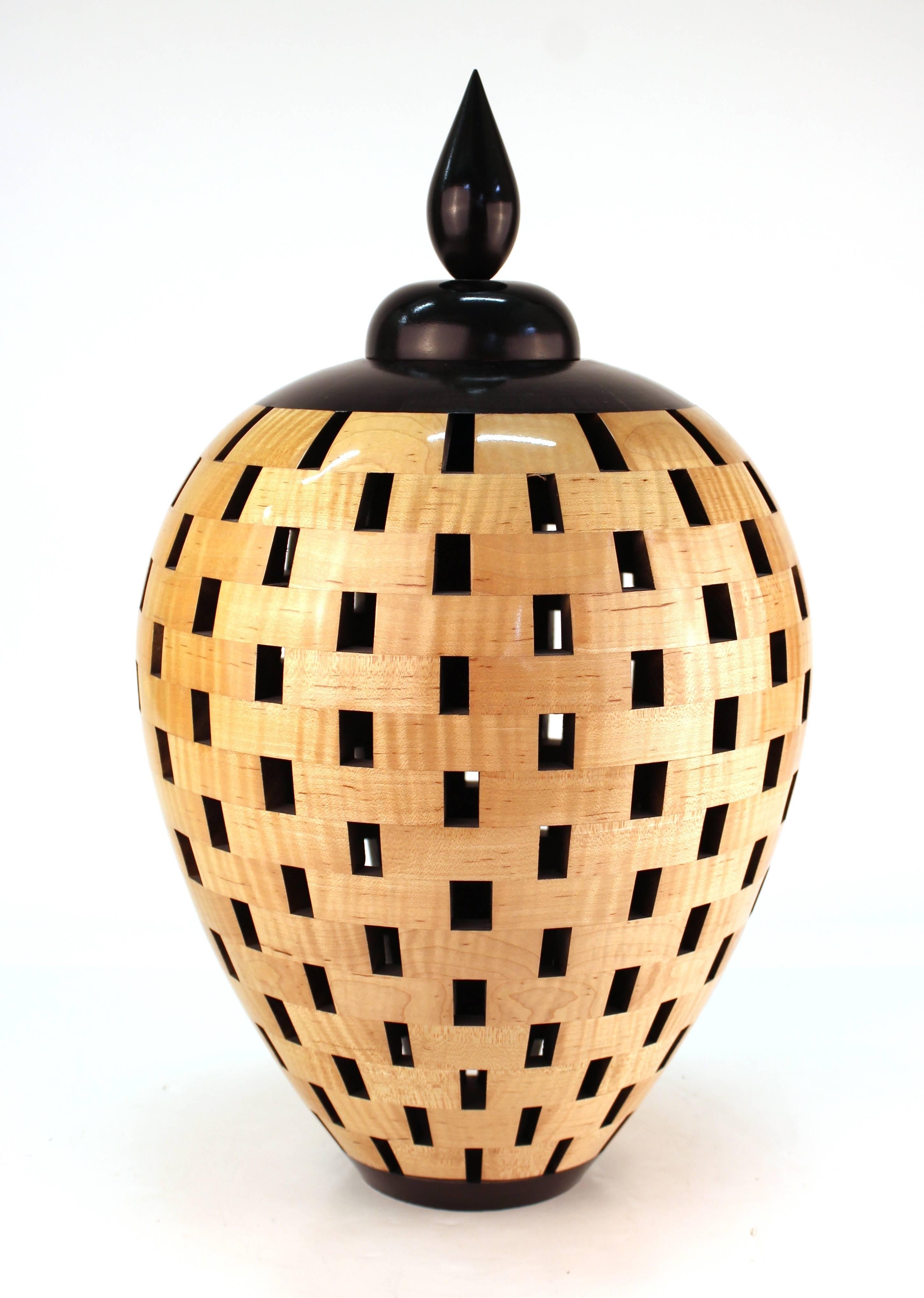A wooden lacquered vessel with lid, created by Joel Hunnicutt. The vessel has open segments, which is representative of Hunnicutt's creative style. The piece is in great condition.