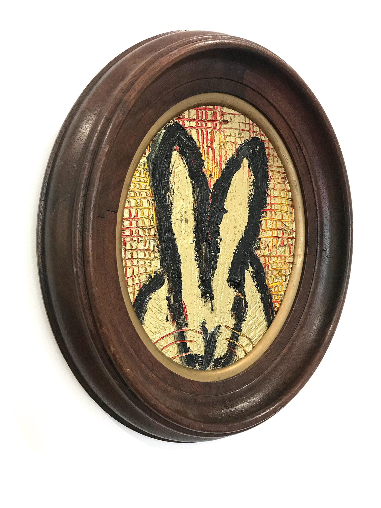 A wonderful composition of one of Slonem's most iconic subjects, Bunnies. This piece depicts a gestural figure of a black bunny on a gold background with thick use of oil paint and red accents. It is housed in a wonderful oval antique 19th Century