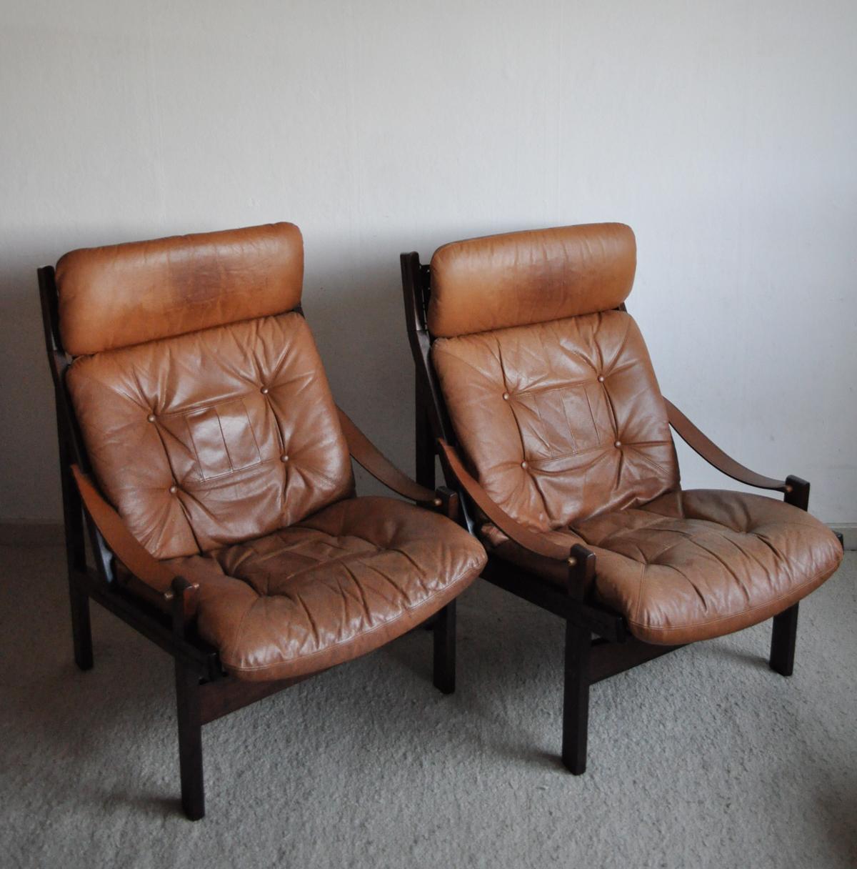 Hunter lounge chair with cognac brown leather and stained hardwood frame. Canvas weave holding the leather cushion up.
Designed in the 1960s by Norwegian Torbjørn Afdal for Bruksbo.
Good vintage condition. Patinated with signs of wear consistent