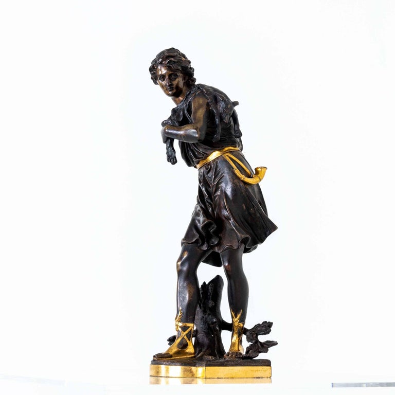 Partially gilded bronze figure by Eutrope Bouret (1833 Paris - 1906) in the form of a hunter with wolf pelt over his shoulder standing on a naturalistic landscape base. He holds a spear in his hand (damaged) and a hunting horn hangs from his hip.