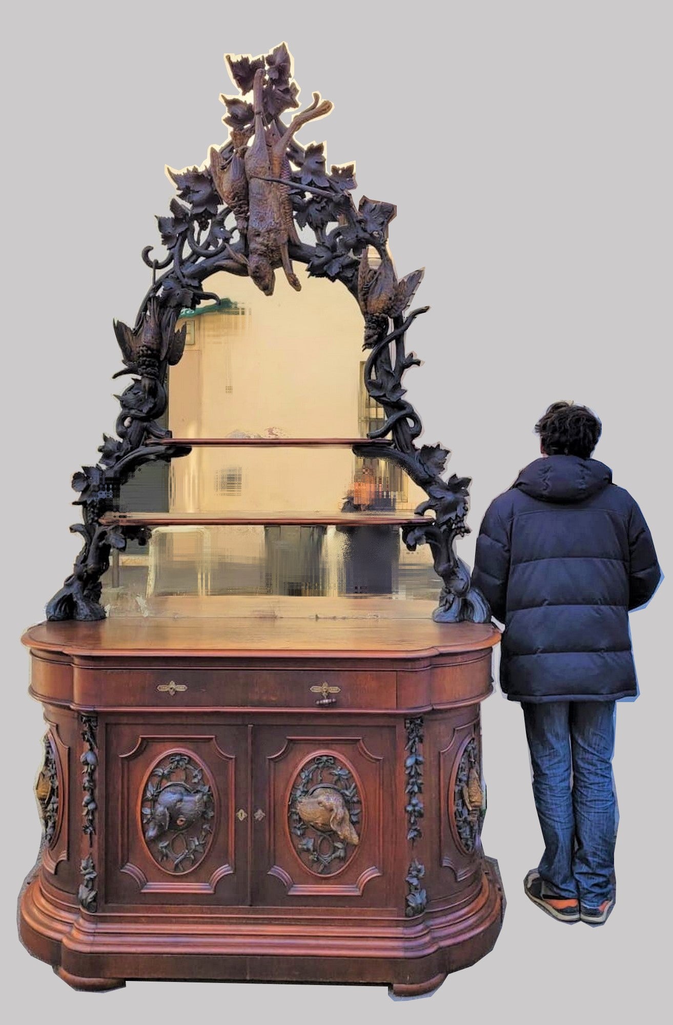 Large hunting sideboard surmounted by a spectacular mirror carved with trophies

Large sideboard in oak and mahogany veneer, opening in front with 2 doors and 1 drawer, rounded sides: the doors are decorated with medallions with dog heads in