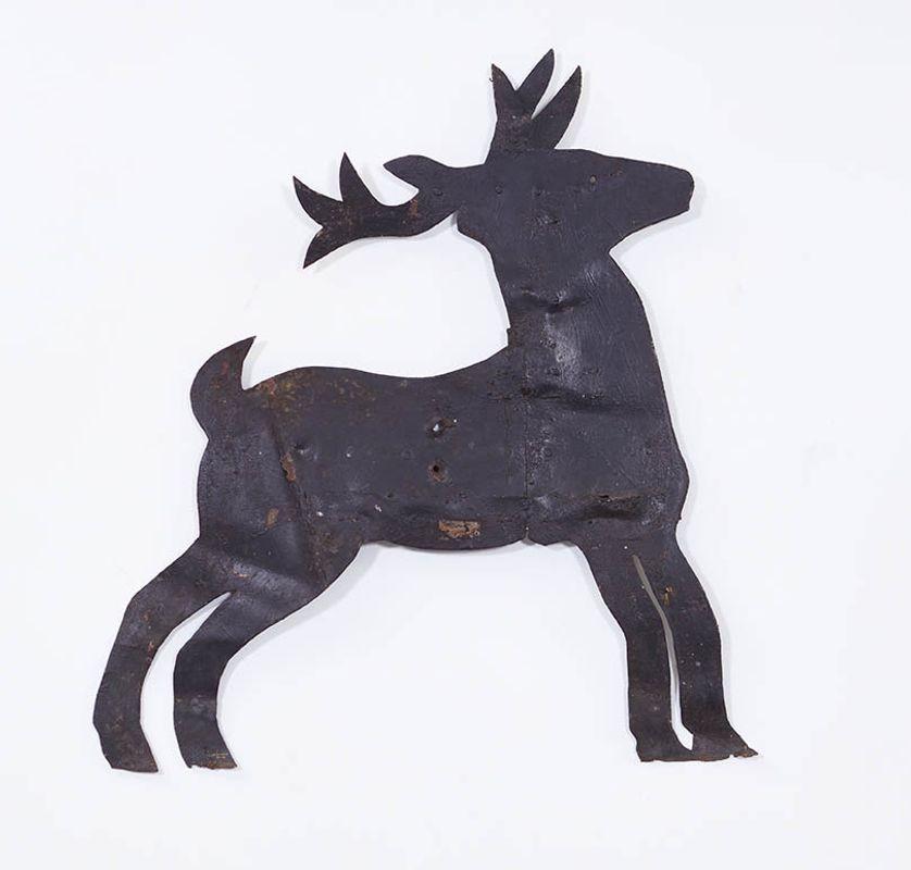 A folk art sheet iron weathervane in the shape of a stag.  Pleasing naive depiction of form with antlers, 'shoe' hooves and tail.  Hand-made body and iron supports to back.  Dents and bullet holes to surface and in old black paint.  Reputedly from a