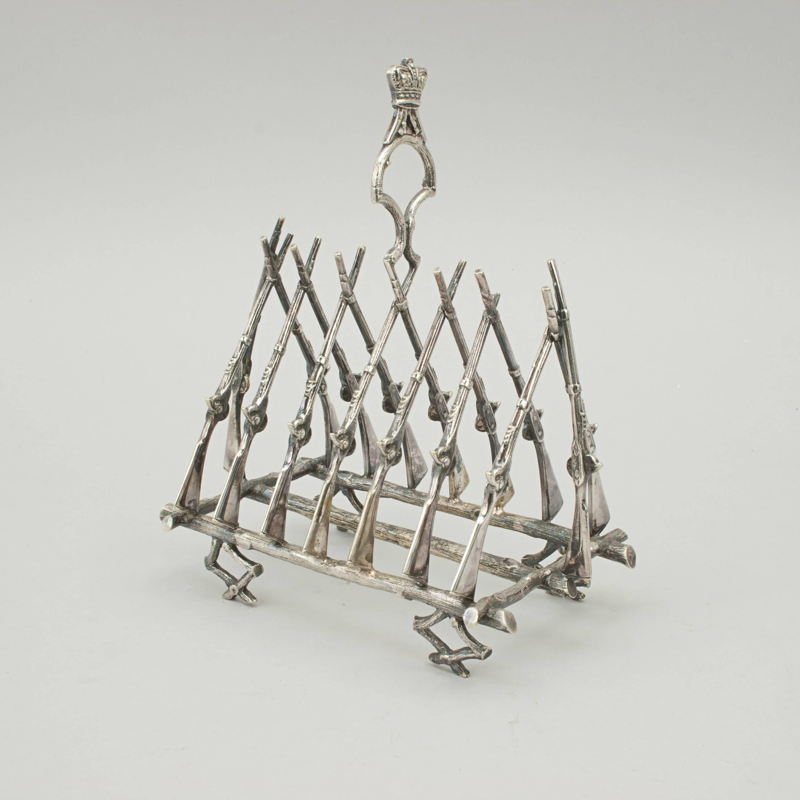 A silver plated shooting toast rack which can also be used as a letter rack or napkin holder. The dividers are in the shape of crossed flintlock rifles. The base is made up of crossed logs. A nice looking toast rack for six slices.