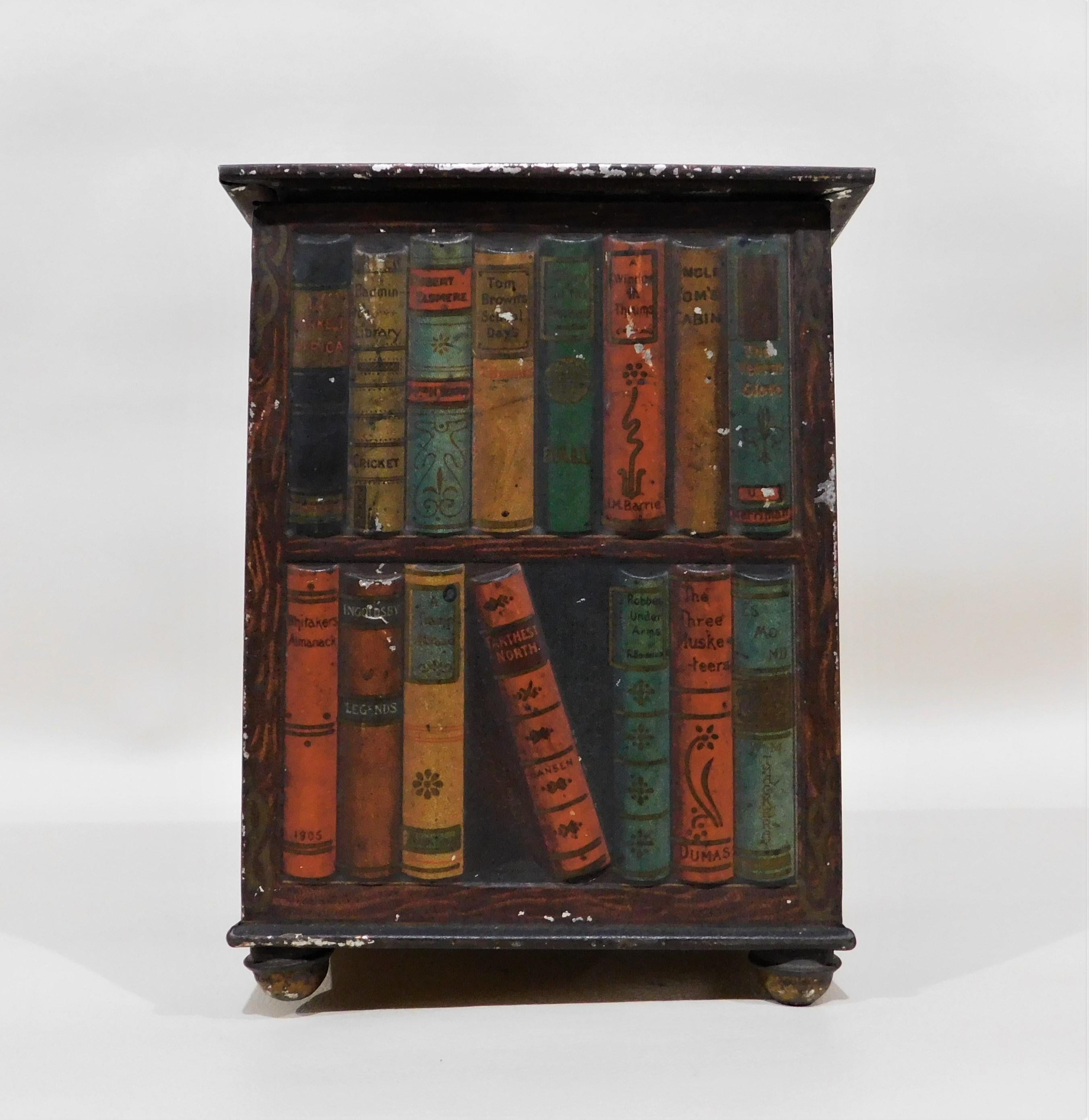 Rare Huntley and Palmers lithographic hand-painted biscuit tin box in the shape of a book stand/case, with books and bindings viewed from all sides, and raised on bun feet. The lid lifts to reveal an engraved marking that reads: 