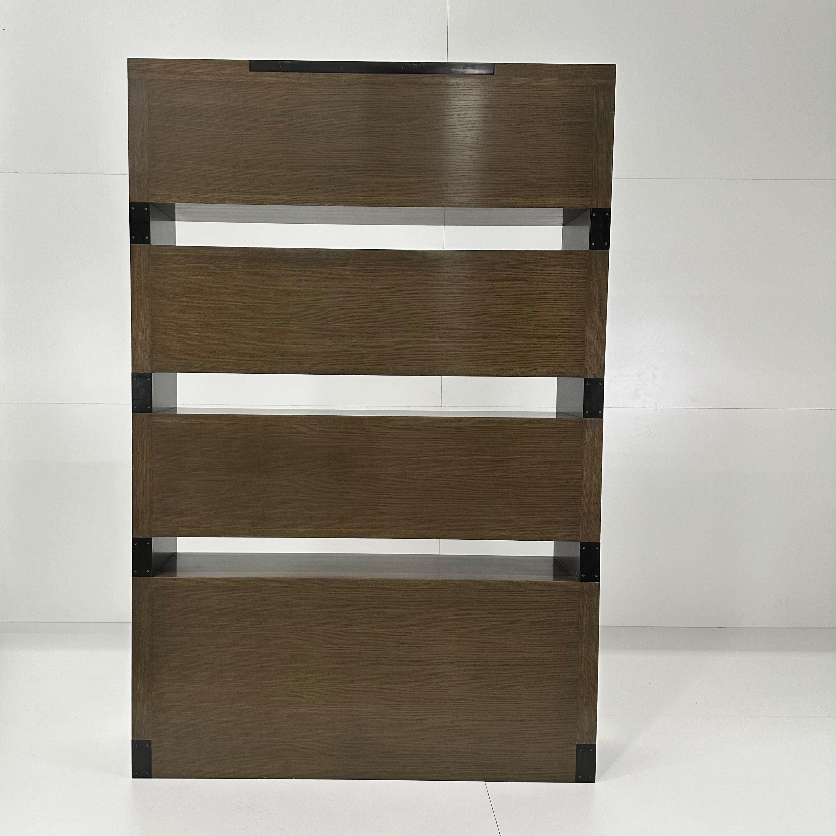 This architectural bookcase system features a playful sequence of shelves at alternating heights. Composed of wood and precisely fitted metal elements, it features shelves and closed cabinets which offer creative ways to store and display books,