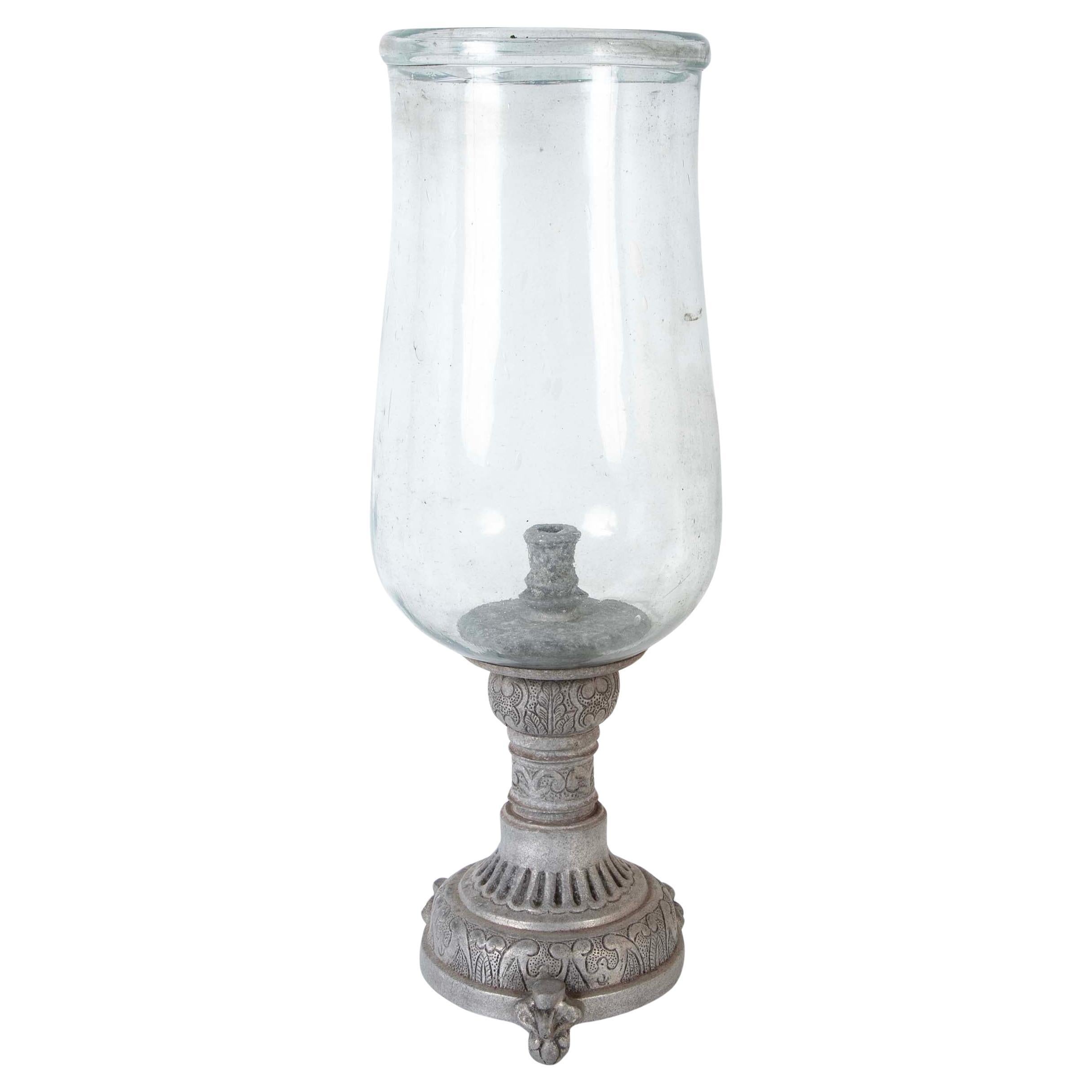 Hurricane lamp with large scale hand blown glass shade mounted on a tripod zinc base with abstract and floral motifs. This handsome photophore makes quite the impression, standing over two feet tall. 
26.5 inches high 11.5 wide 


