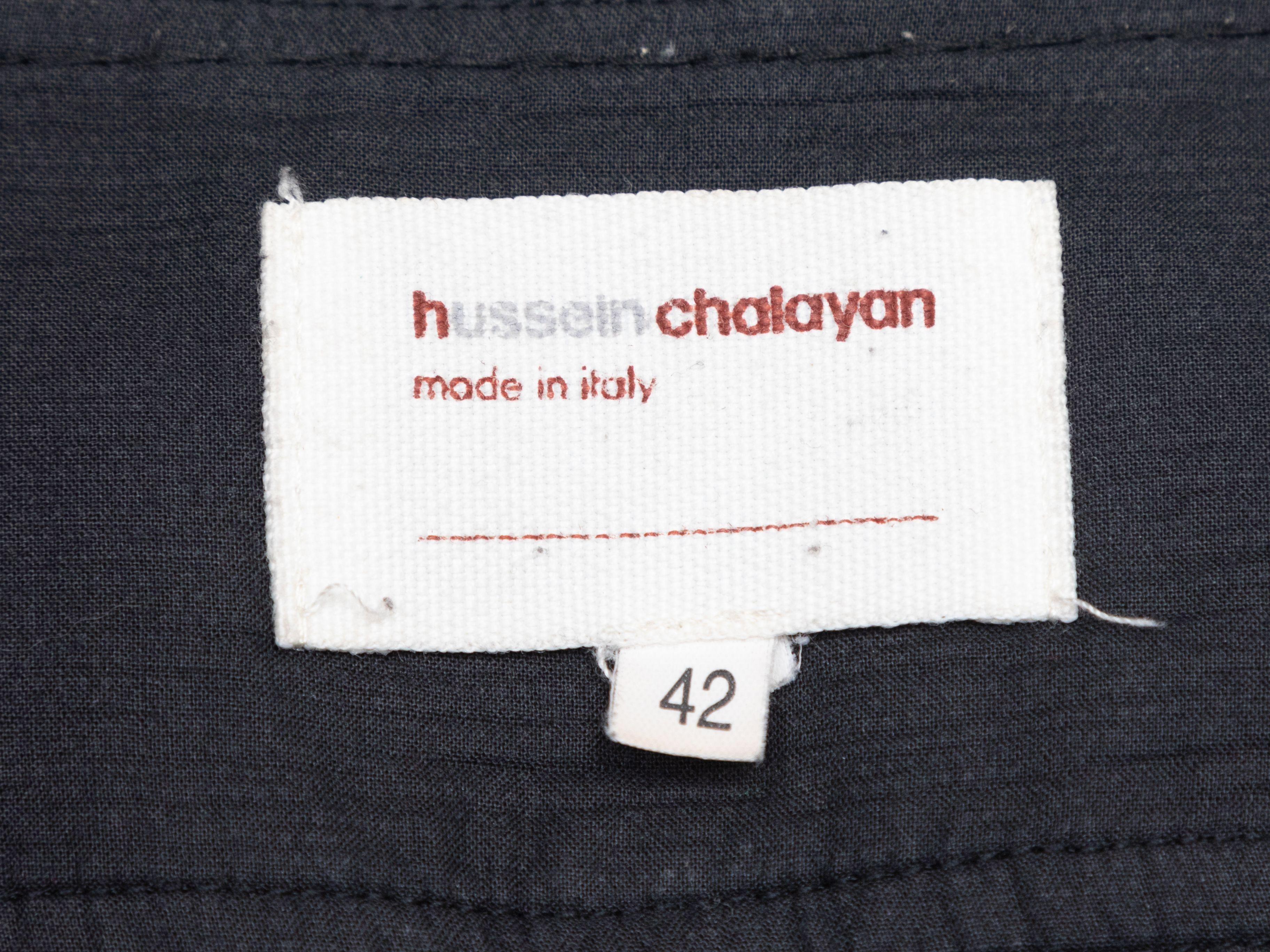 Product Details: Black pleated Bermuda shorts by Hussein Chalayan. Three pockets. Zip closure at front. Designer size 42. 33