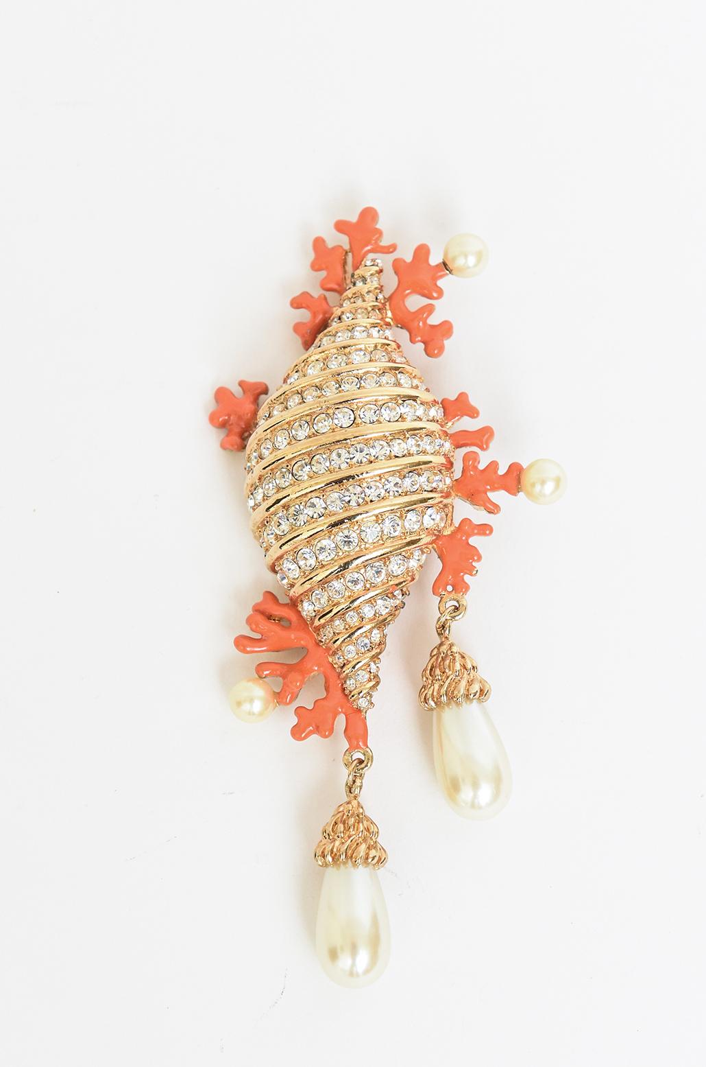 This stunning, rare signed and hallmarked Hutton Wilkinson pin and or brooch is a seashell of the gorgeous combination of coral enamel faux pearl, gold plate and rhinestone. It is hallmarked with his initials of H and W and a crown and says Made in