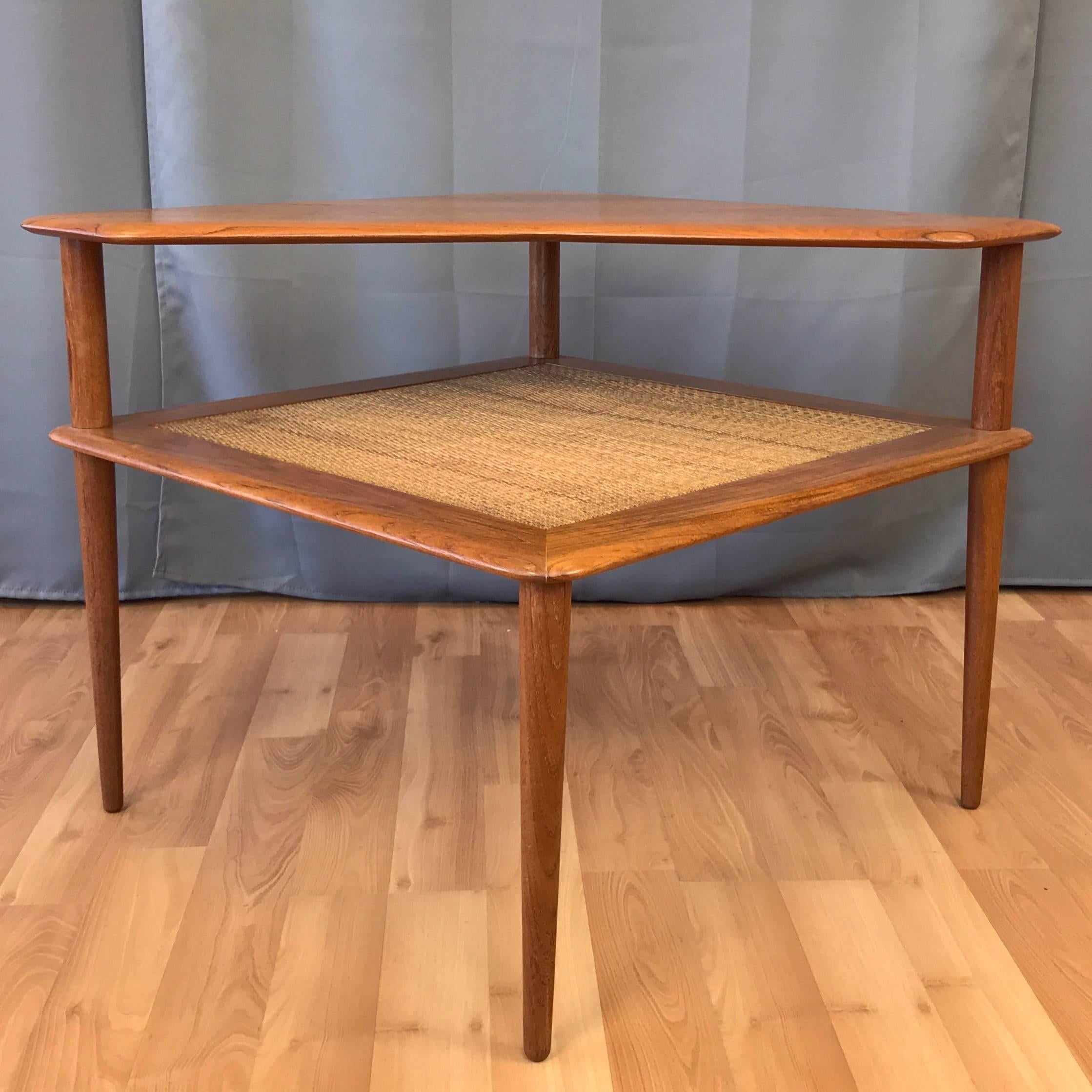 A Scandinavian Modern teak and cane “Minerva” corner or end table by Peter Hvidt & Orla Mølgaard-Nielsen for France & Søn.

Solid teak square two-tier table with new vintage-finish woven cane lower level and cut-away upper level. Smoothly tapered
