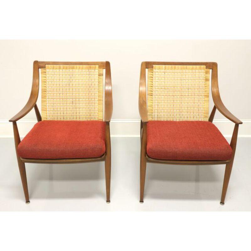 A pair of classic Mid 20th Century Danish Modern lounge chairs by Peter Hvidt and Orla Molgaard Nielsen for John Stuart. Teak frame, woven rattan back, curved arms, plastic encased metal springs seat support, burnt orange colored fabric upholstered